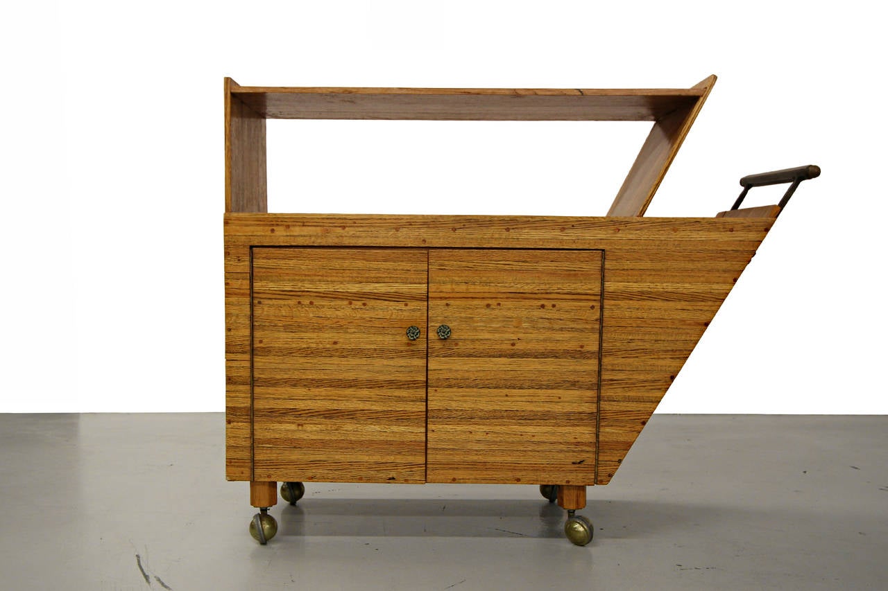 Super rare and super cool, hand crafted oak rolling bar cart.  Bar cart is constructed of individual oak pieces held together with wood dowel pegs.  It has beautifully detailed brass door pulls and a solid brass cart handle.  The inside of the cart