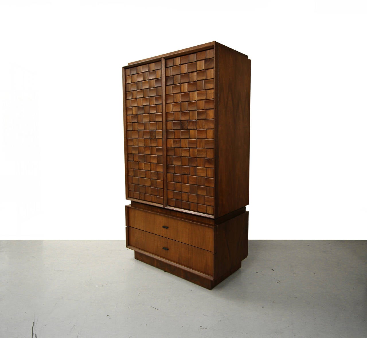 Beautiful walnut armoire style dresser piece, made in Canada.  Front is constructed of alternating sculptural blocks creating a dimensional pattern that is truly unique.  Unit is 2 separate pieces.  The top piece has two doors that conceal three