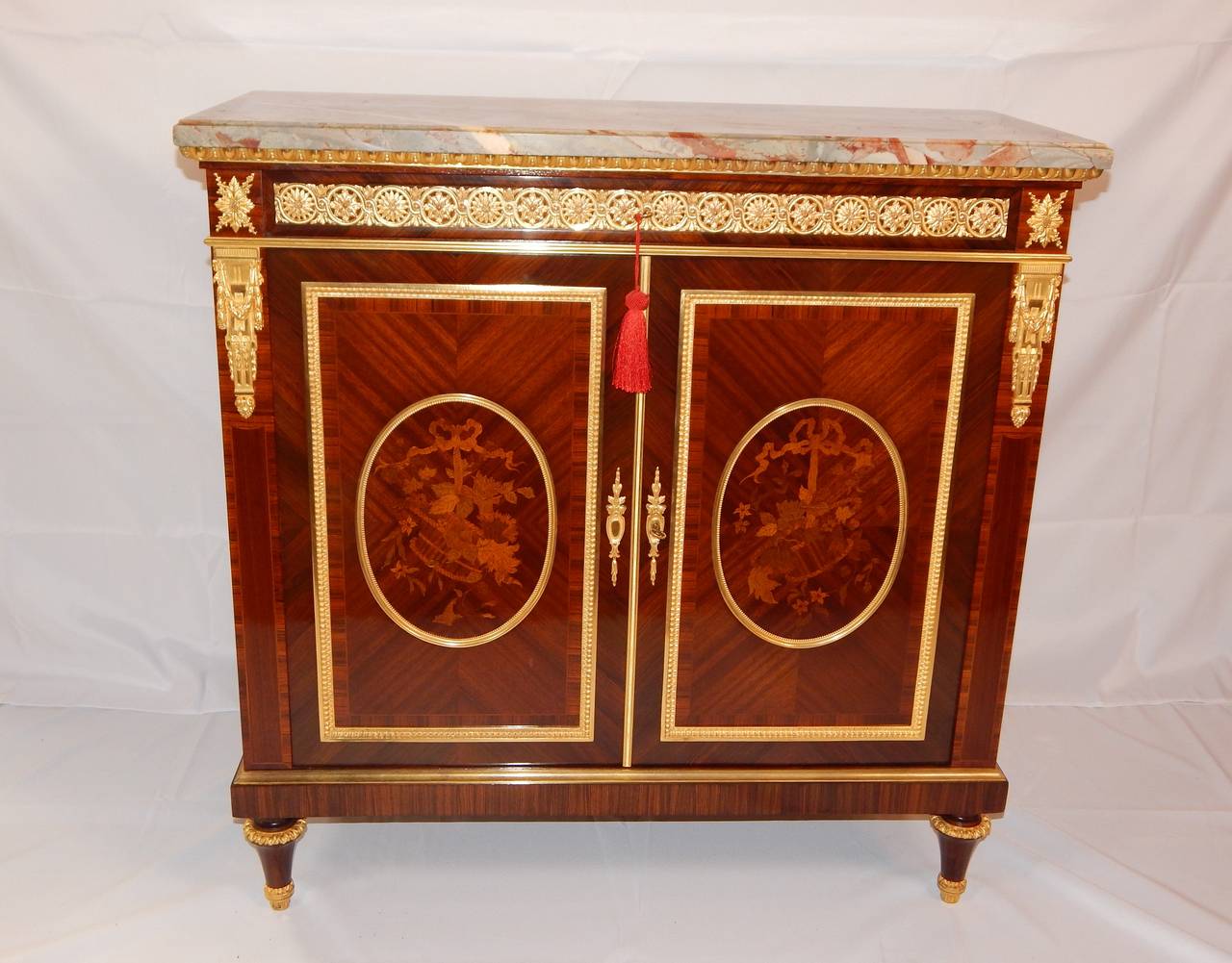 A fine quality bronze mounted marquetry inlaid cabinet, or commode, having two doors, with one drawer above, along with interior drawers. Both the bronze mounts, and the marquetry are of the finest quality, as would be expected from this highly