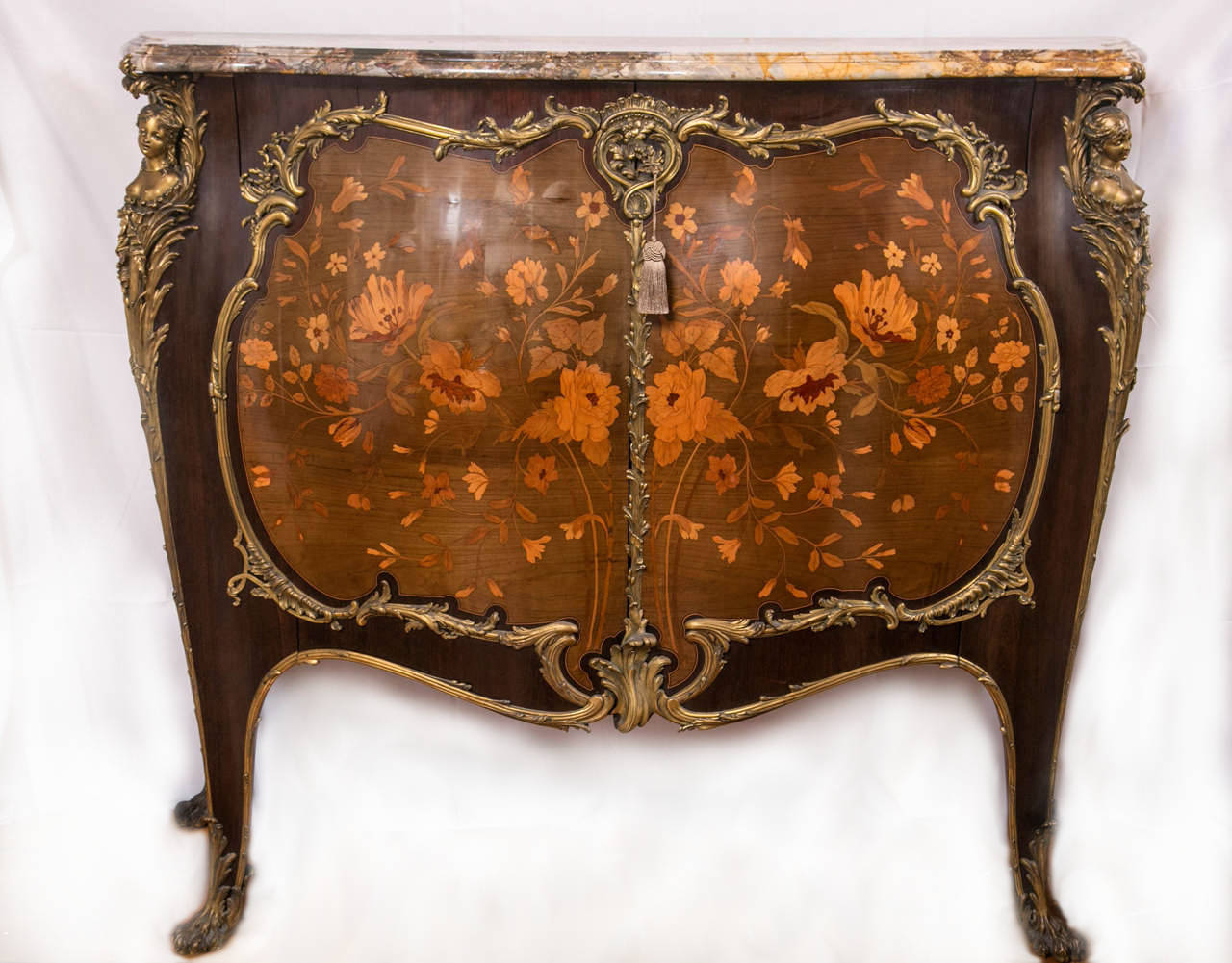 An extremely fine and important bronze-mounted marquetry inlaid two door commode or cabinet, signed, Jansen, with the bronzes stamped ZN. Standing on tall legs, this incredible marble top piece has a beautiful serpentine shape, as well as bombe.