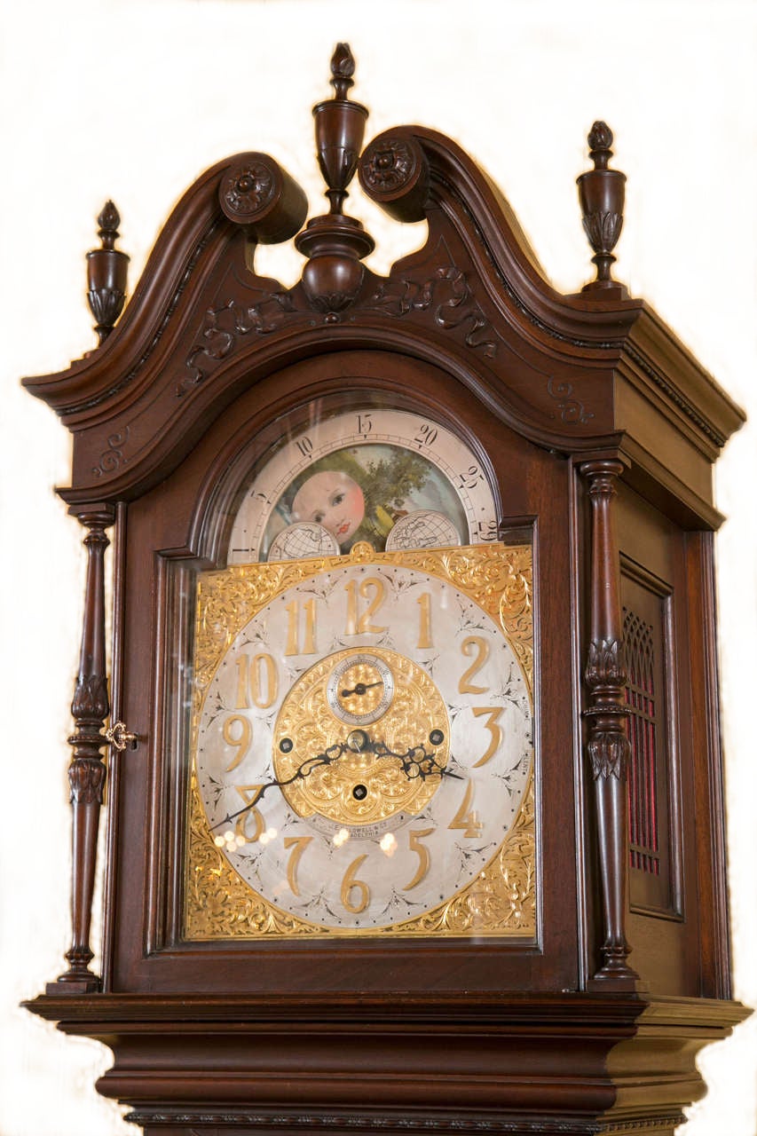 A beautifully carved mahogany grandfather clock, with a broken arch pediment top and finials. Beveled glass door reveals the original pendulum, along with the three brass weights. Signed J.E. Caldwell, with a very fine movement, as well as a