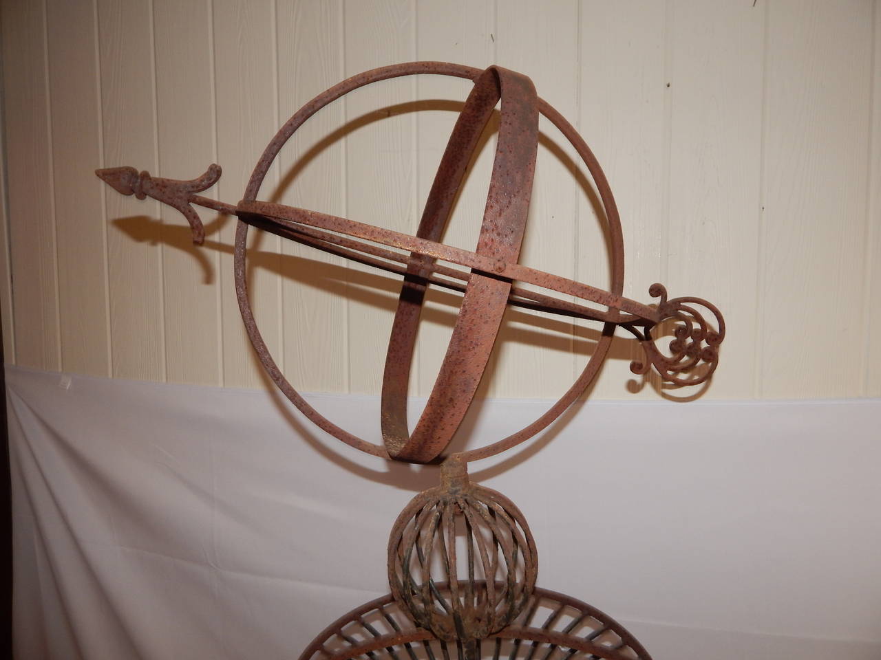 A cast iron armillary on stand with three spheres and an arrow.