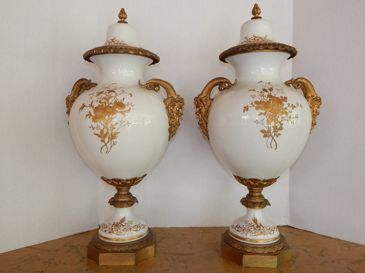 A beautifully painted pair of Sevres bronze mounted covered vases, on a cream white ground, with Bacchus handles, artist signed.