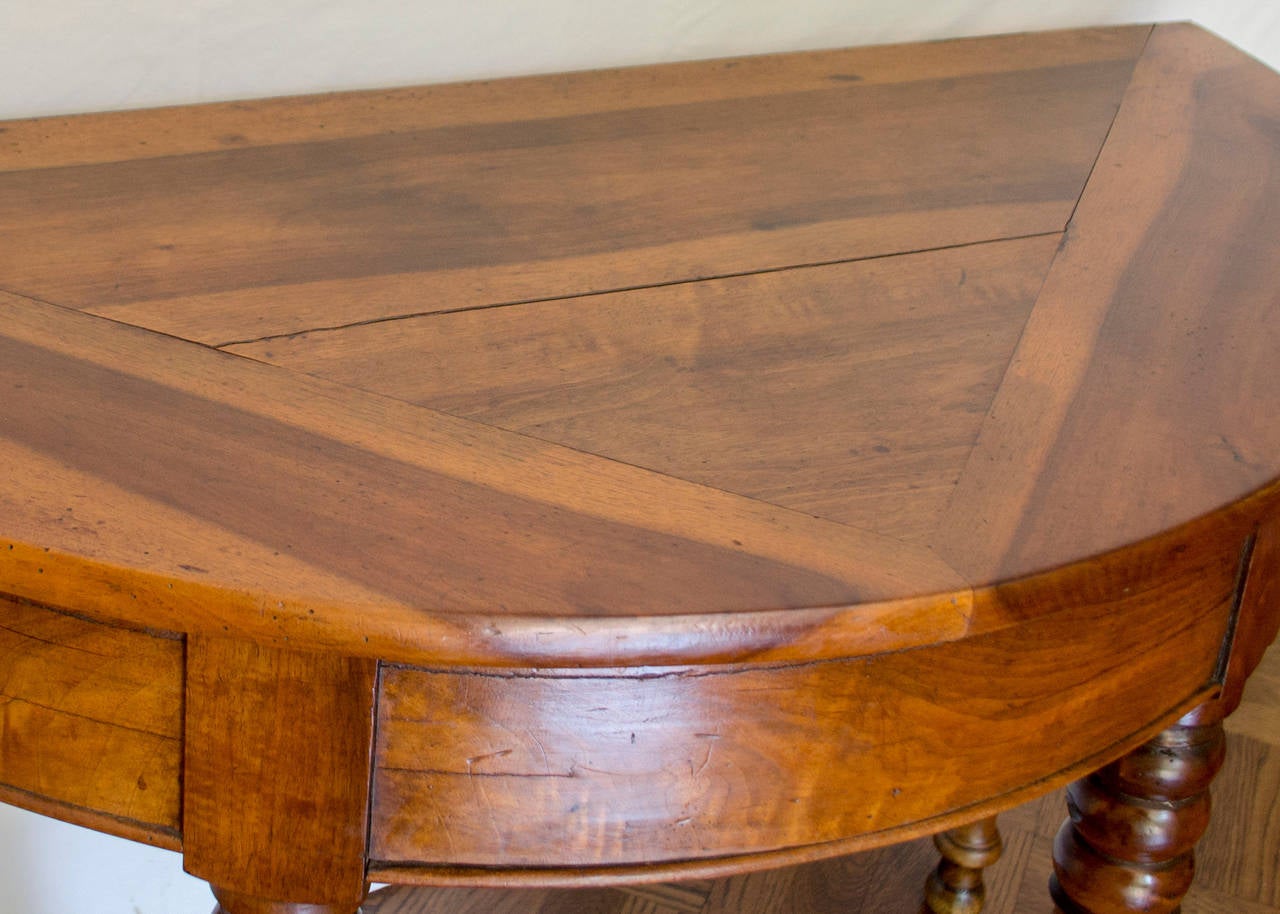 This 19th Century French Walnut Demilune Table on turned legs has a unique triangular wood inlay design on it's top.  The wood patina is beautiful and the legs are in excellent condition.