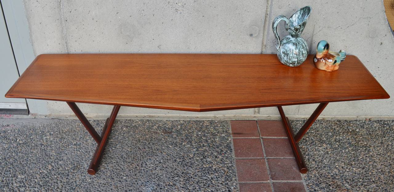This impeccably made Danish modern teak coffee table is attributed by Mogens Kold and has a unique trapezoidal shaped top with a flared lip on the triangular end--perfect for in front of the sofa, with two chairs angled towards the triangle of the