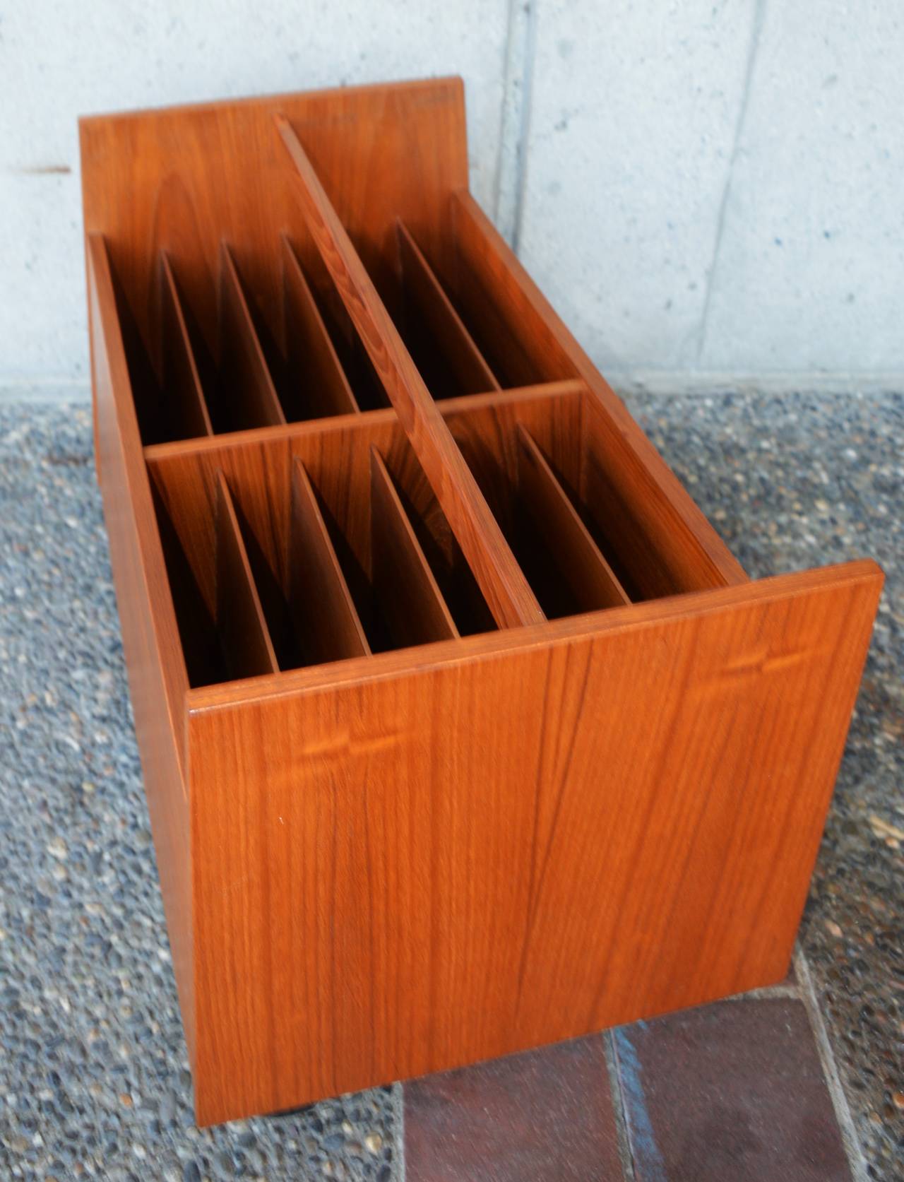 This Danish modern teak storage cart is the super rare double wide version, made by Rolf Hesland for Bruskbo. Featuring an overall trapezoidal shape that tapers upwards, generous slots for vinyl, magazines, or office filing, with a handy handle and