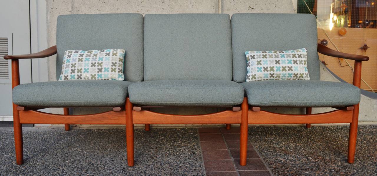 This gorgeous Danish Modern teak frame sofa by Fabian has stunning detailing throughout. Note how the center legs at the back and the front protrude through the cushions, showing a reveal of the wood between the seats. The thick and contoured arced