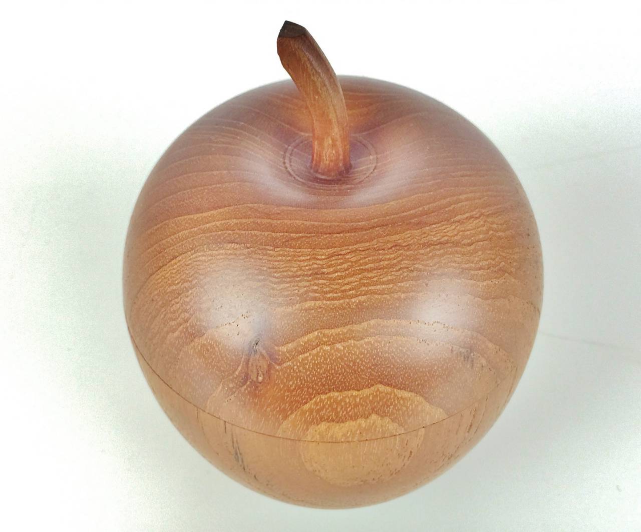 This lovely little apple shaped box is beautifully turned from a solid piece of teak, finely hewn and with a well fitting lid. Even the little apple stem and the bottom of the apple are very lifelike. In amazing condition and with a lovely warm