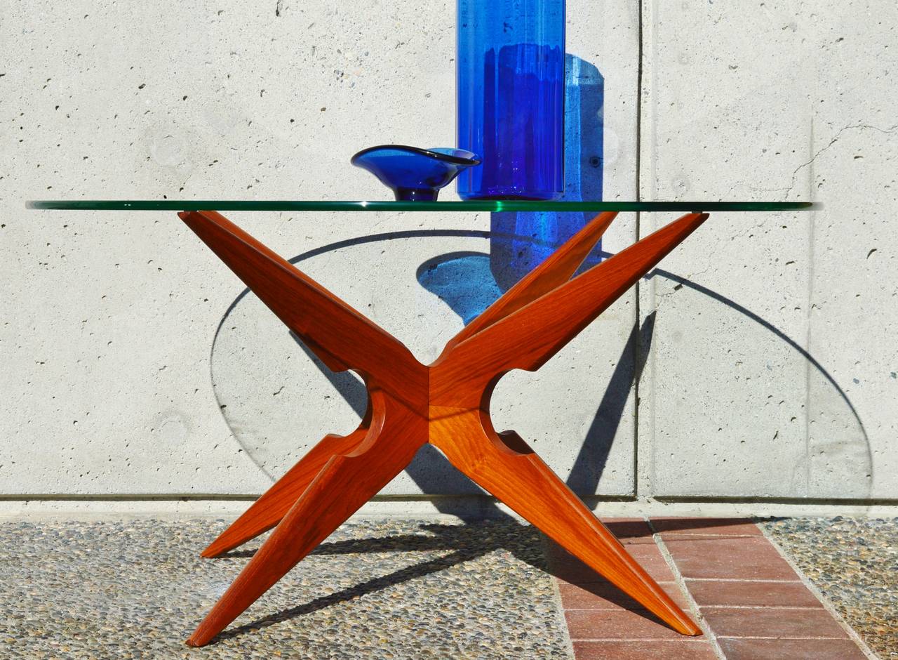 This killer spider leg X-base Danish modern teak coffee table has breathtaking lines! Certainly in the style of Vladimir Kagan and Adrian Pearsall, and featuring a two part base that slots together tightly to form the star, and a round glass table