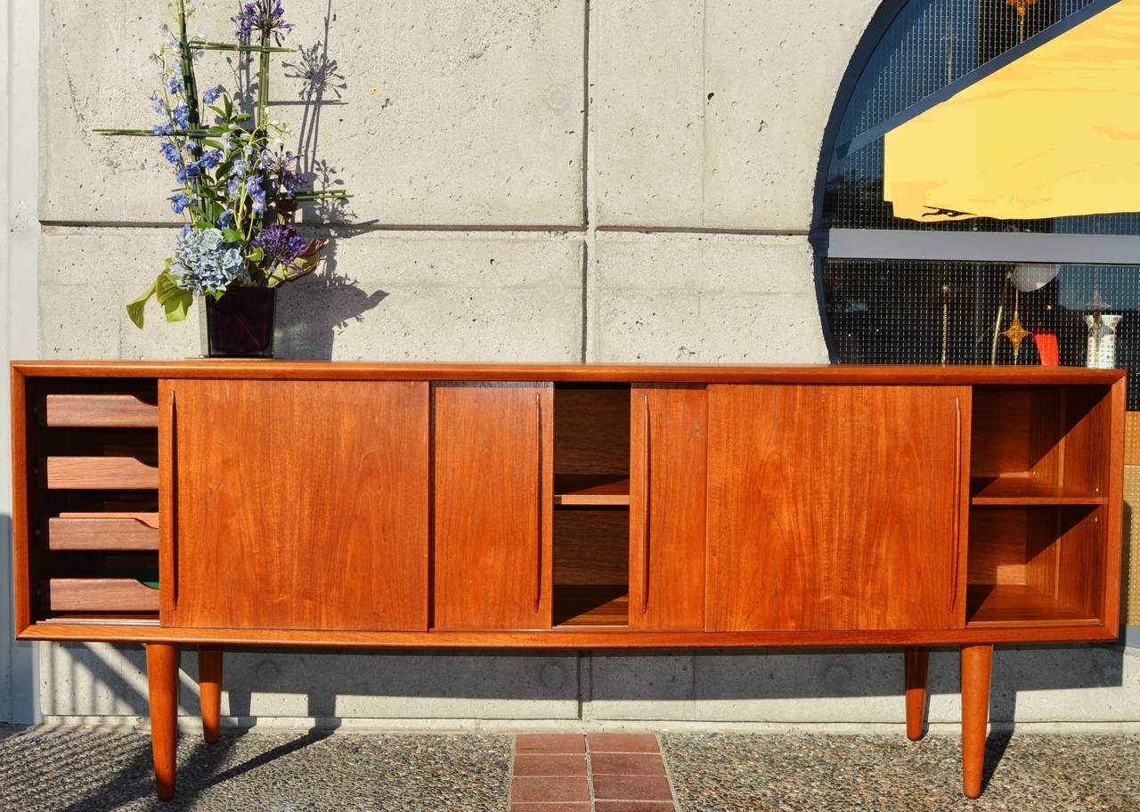 This totally stunning, top quality teak buffet or credenza has a gorgeous rich patina and is a unique bow-front design where the front is deeper and curves back at the sides. Designed by Arne Vodder for H.P. Hansen, it features four sliders with