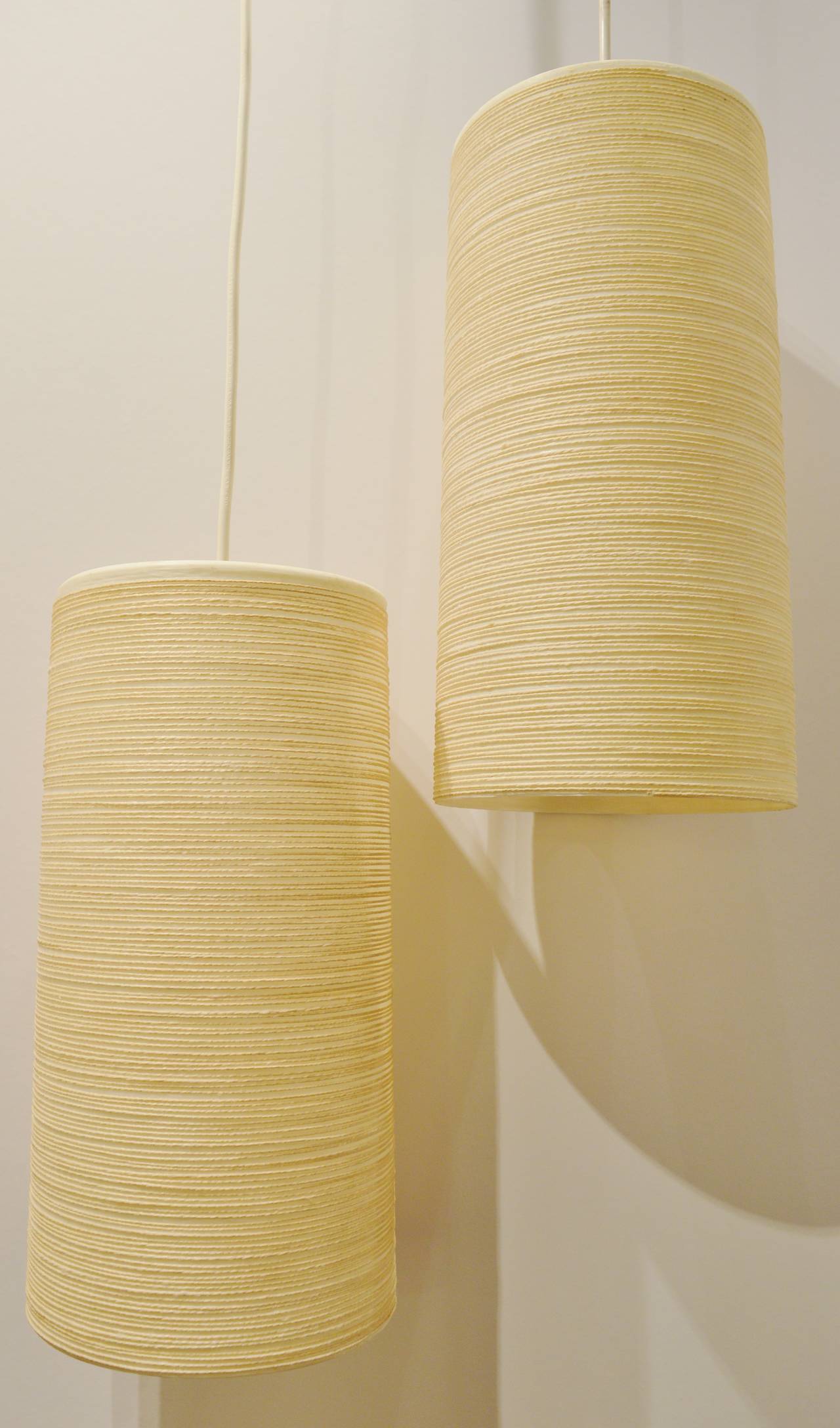 This stellar pair of Danish Modern organic cylinder swag lights are by Lotte & Gunnar Bostlund, Danes who moved their business to Ontario, Canada. Their trademark woolen thread applied around the outside and the inner fibreglass shell shade give off