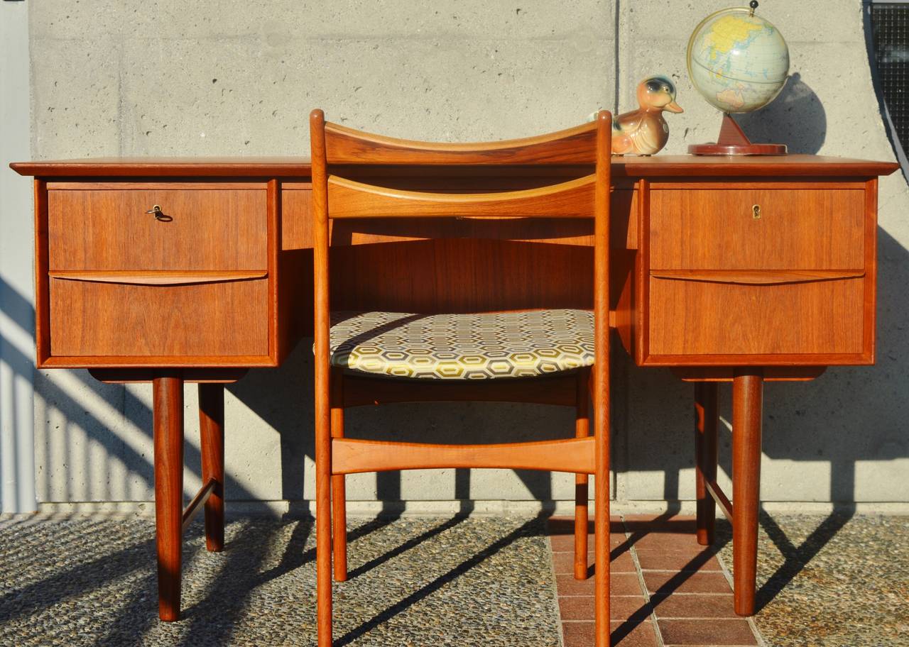 This stellar Danish Modern teak desk is all hardwood construction and super styling! Featuring a double pedestal with 2 drawers on either side and one in the middle, with birch drawer frame construction and a skeleton key to lock the top 3 drawers.