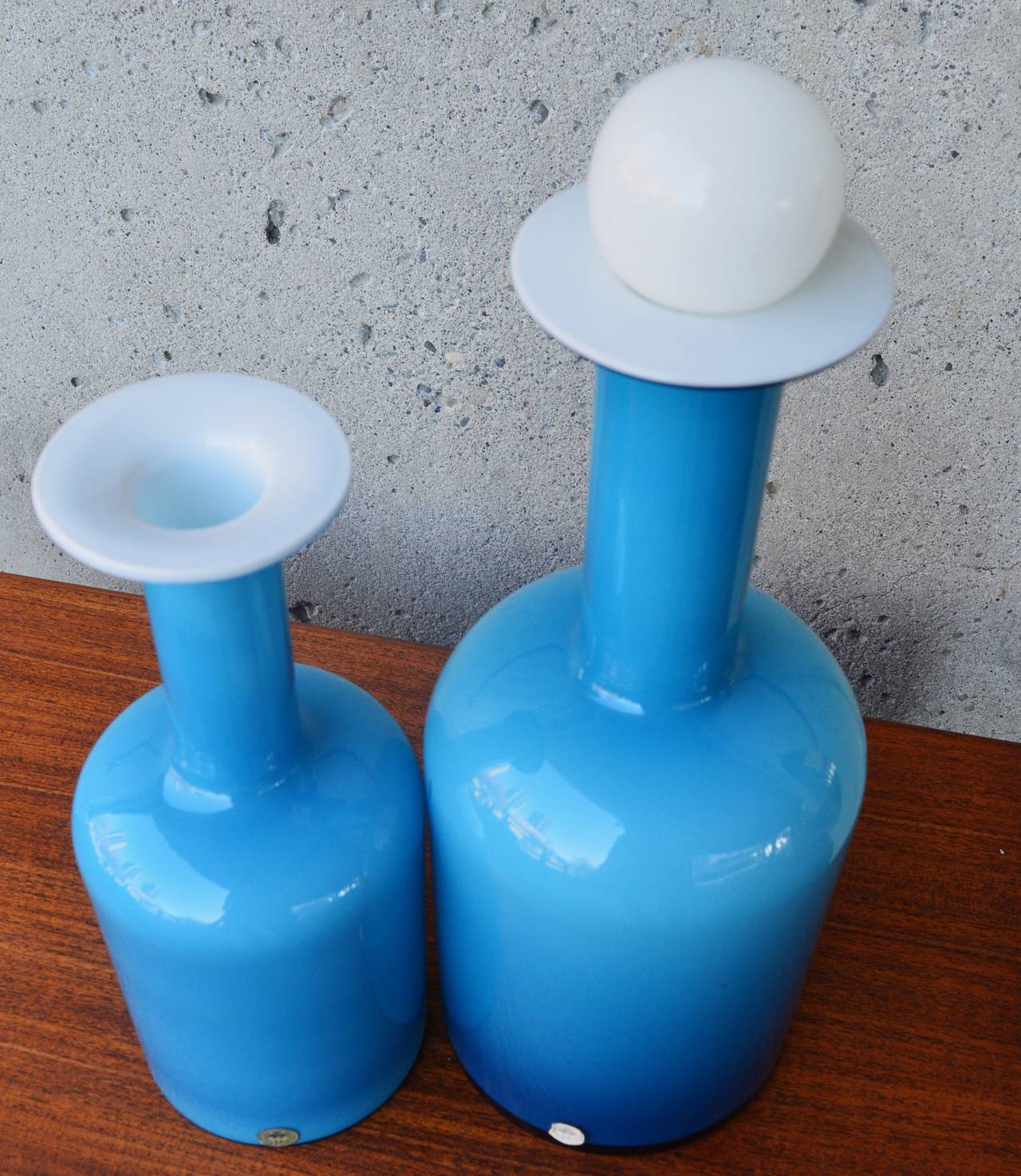 This stellar pair of striking turquoise glass gull vases--one with the rare finial, were designed by Otto Brauer for Holmegaard.  Cased in white, it gives the glass a beautiful translucent sheen.  Both are in excellent condition with the original