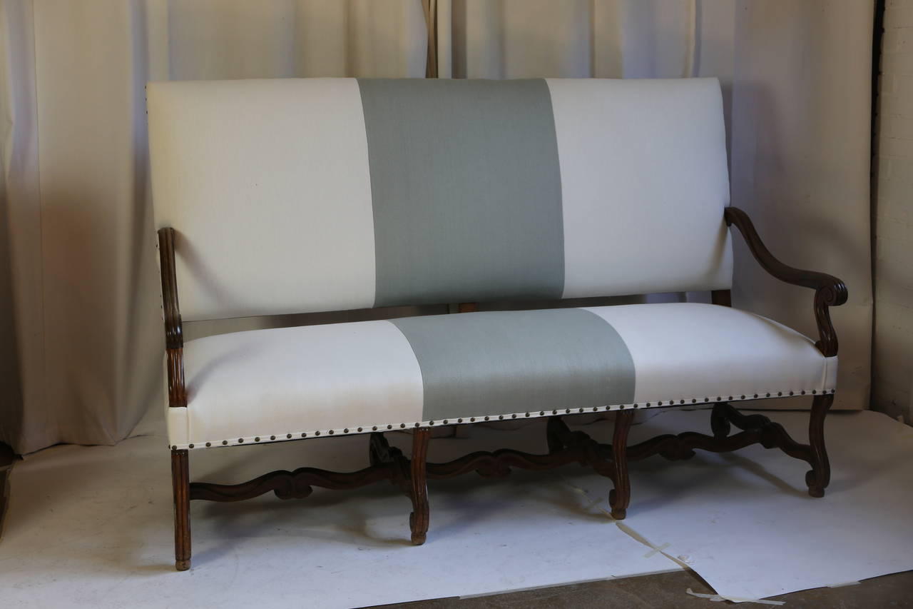 French three-seat sofa in the style of Louis XIV, circa 1890. Solid walnut frame newly upholstered in linen with self tape and nailhead detail. The S-carved legs are joined by stretchers.