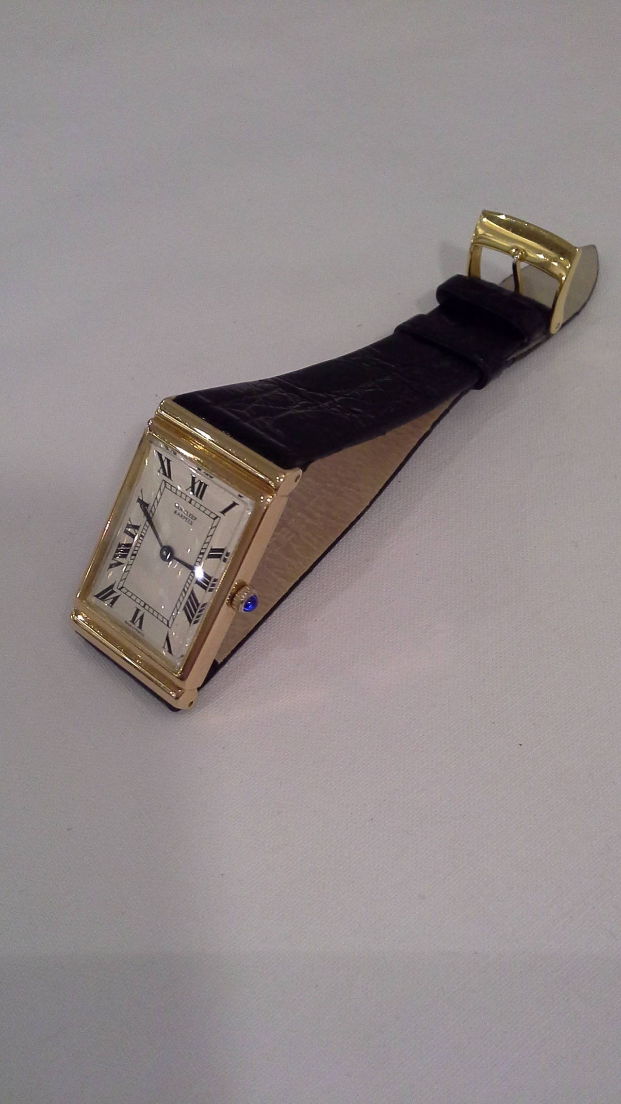 Van Cleef & Arpels 18k Yellow Gold Wristwatch with a Cabochon Sapphire Crown & hidden lugs. The watch is a 17 jewel manual wind movement marked A. Barthelay, unadjusted, Made in France, inside case is marked Alexis Barthelay, France.
The