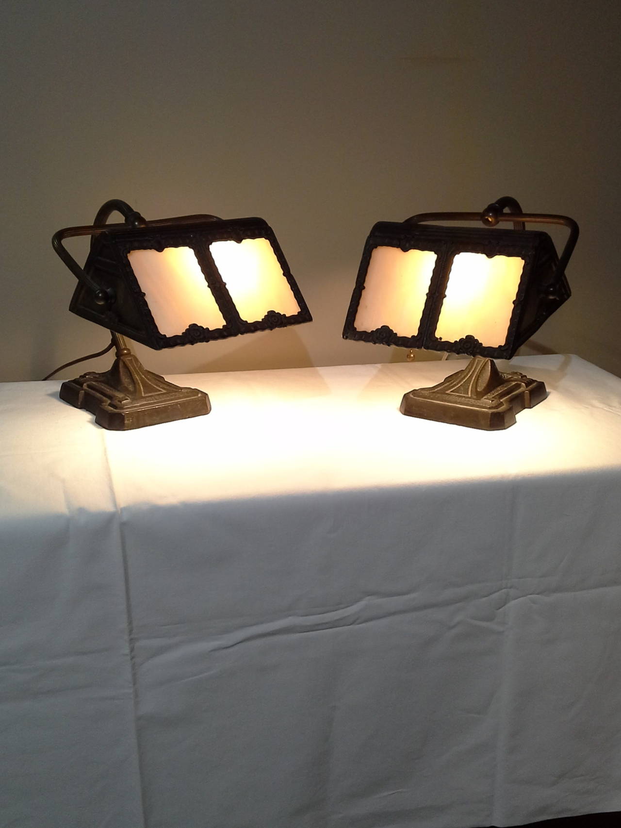 Matched Pair Of Cast Iron Slag Glass Desk Lamps American Circa 1930's, Cast Iron bases with 4 panel in each lamp, Curved back arms, with scrolled decoration and decorative pattern. The lamps measure 9"-inches high x 9"-inches wide x