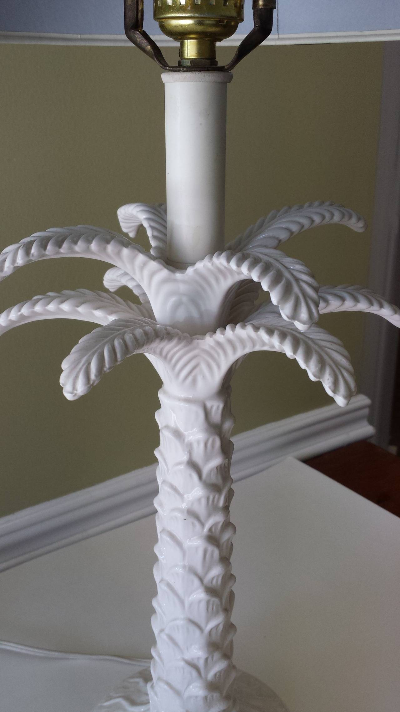 White Porcelain Palm Tree Table Lamp On White Metal Base, There are 2 sets of 4 palm leaves, Bark pattern on the trunk and base. The lamp is 27