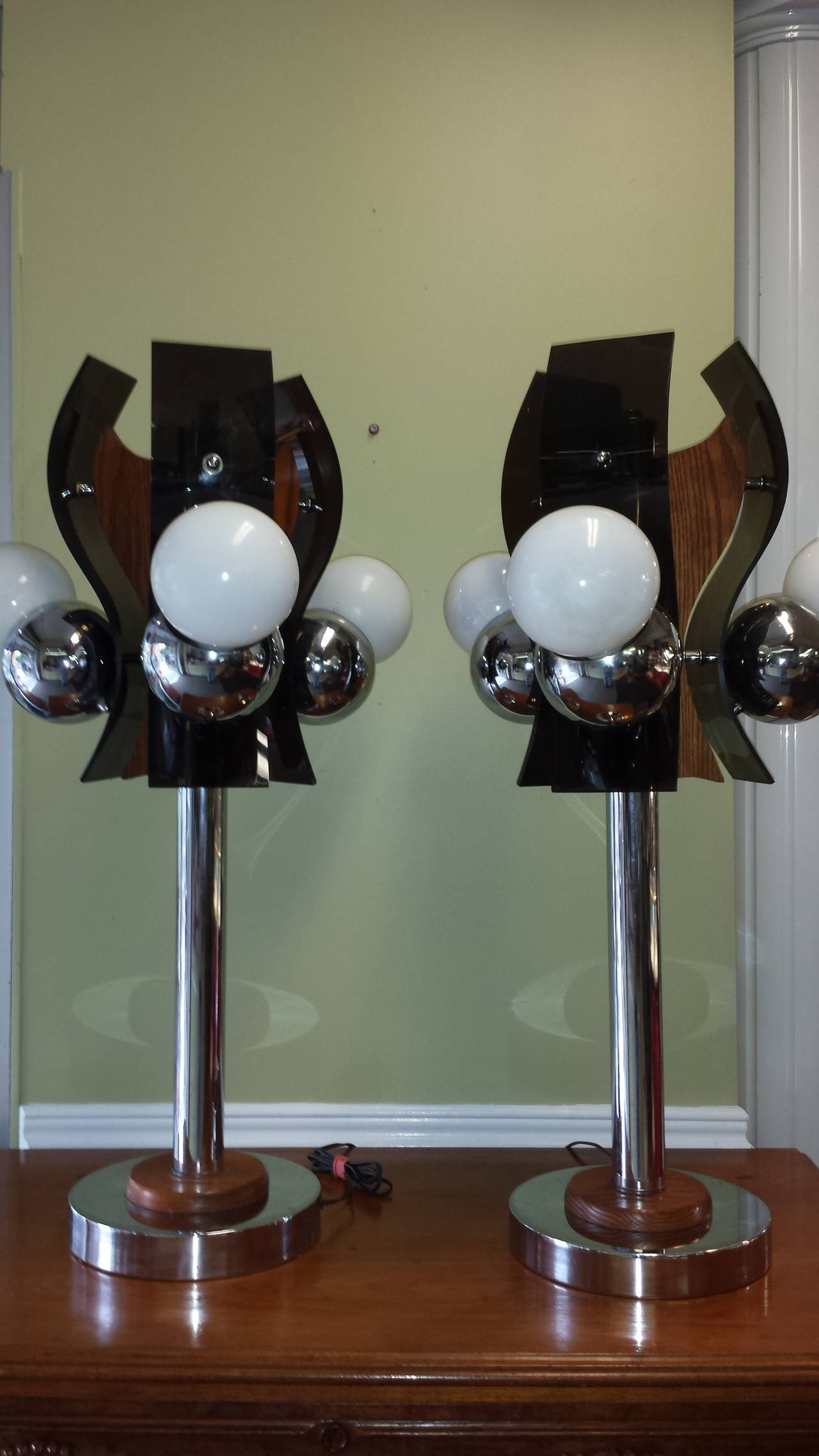 Mid-Century Chrome, Black Plexiglass and Oak Table Lamps Circa 1960's-1970's, with Globe style sockets and bulbs three setting switches on each lamp, one, two or three lights on or off. The smoked black plexiglass is double curved and is mounted on