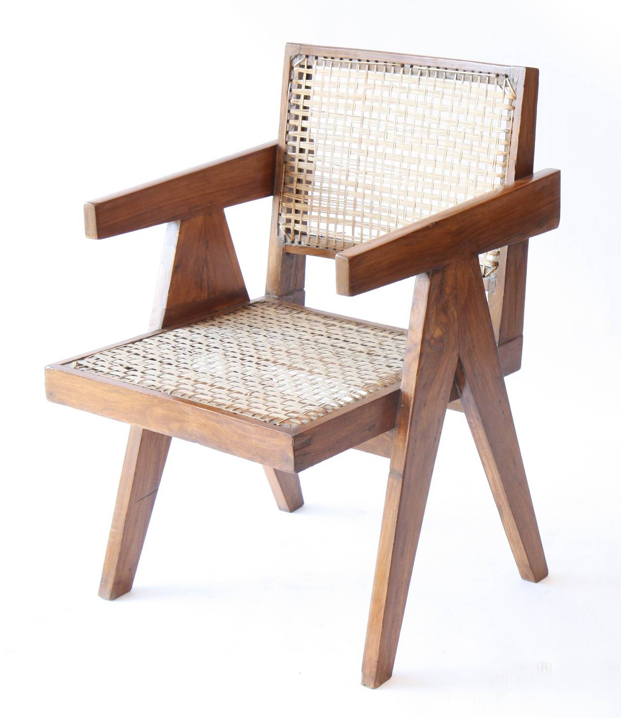 Pierre Jeanneret (1896-1967).
Armchair called "office cane chairs."
In teak, with bended and slightly curved back.
Detached armrests profiled on side compass feet.
The back is fixed to the seat by two small fixtures.
Cane seat and