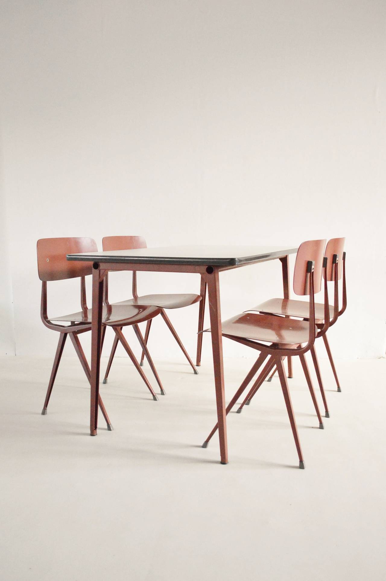 An exceptional one-off custom color dining set designed by Friso Kramer for Ahrend de Cirkel. Having consulted with respected experts in Kramer's work this set is believed to be completely unique with off red legs and fibre seats. It is believed to