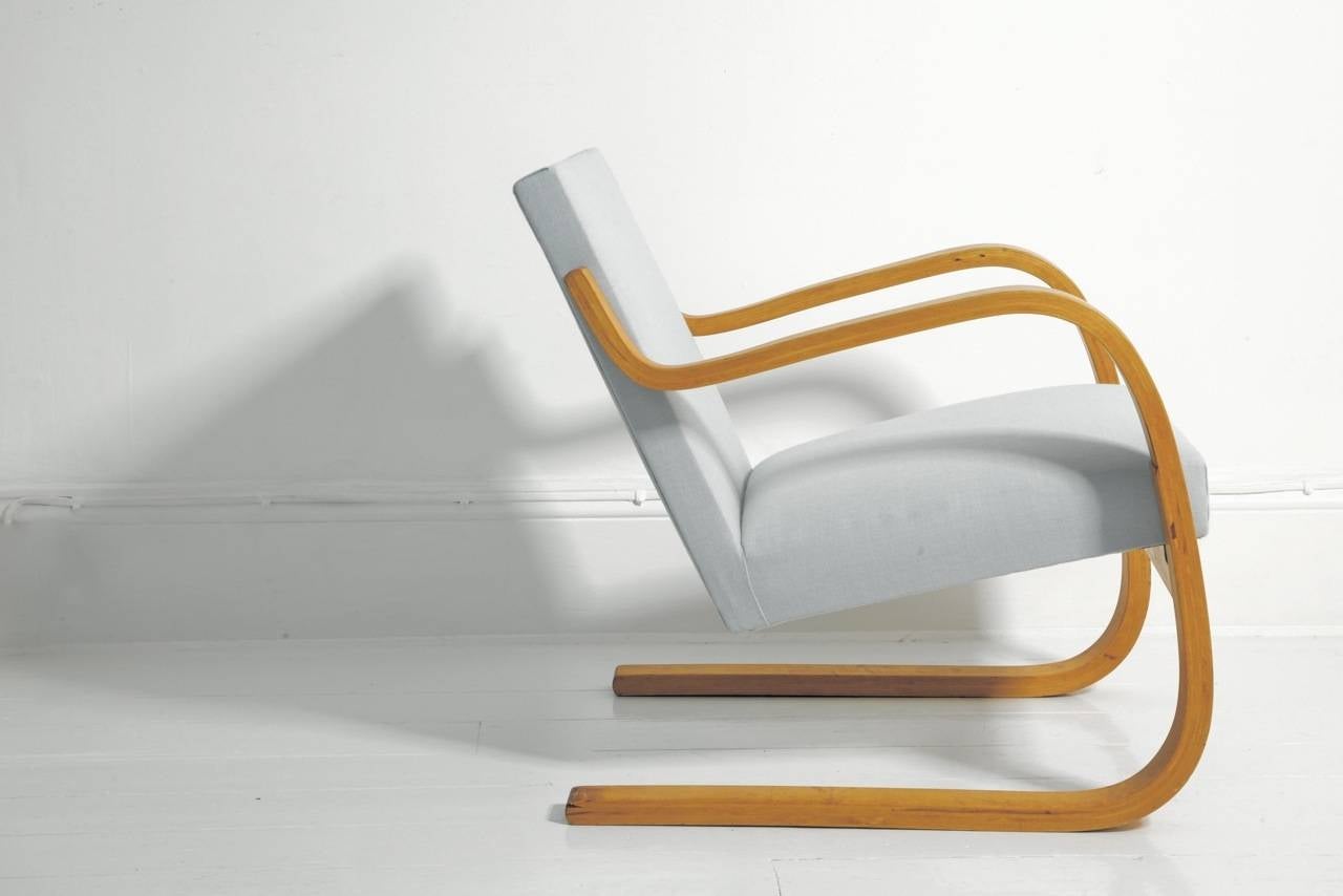 This graceful armchair, designed by Finnish architect Alvar Aalto, has a cantilevered beech bent ply frame with cushioned seating. The Finmar label is present to the underside. Finmar was an official manufacturer supplying pieces specifically to the
