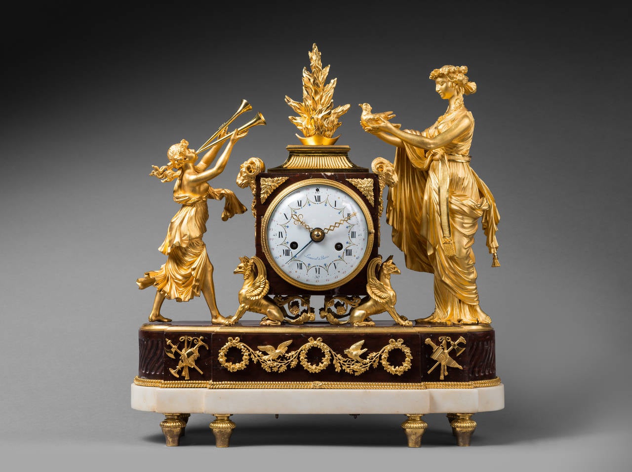Lamiral 
Enamel Dial by Joseph Coteau (1740-1812)
Case Attributed to Pierre-Philippe Thomire (1751-1843)

Rare Gilt Bronze and Rouge Griotte Marble Mantel Clock 
“The Sacrifice to Love”

Paris, late Louis XVI period, circa 1790
Height 46 cm;