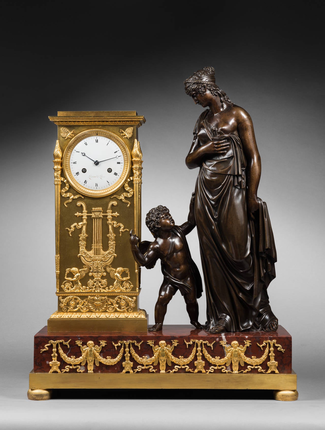 Lesieur 
Case Attributed to Antoine-André Ravrio

Important Gilt and Patinated Bronze Mantel Clock
Venus Guided by Love

Paris, Empire period, circa 1805-1810
Height 59 cm; width 47 cm; depth 22 cm 

The round enamel dial, signed “Lesieur