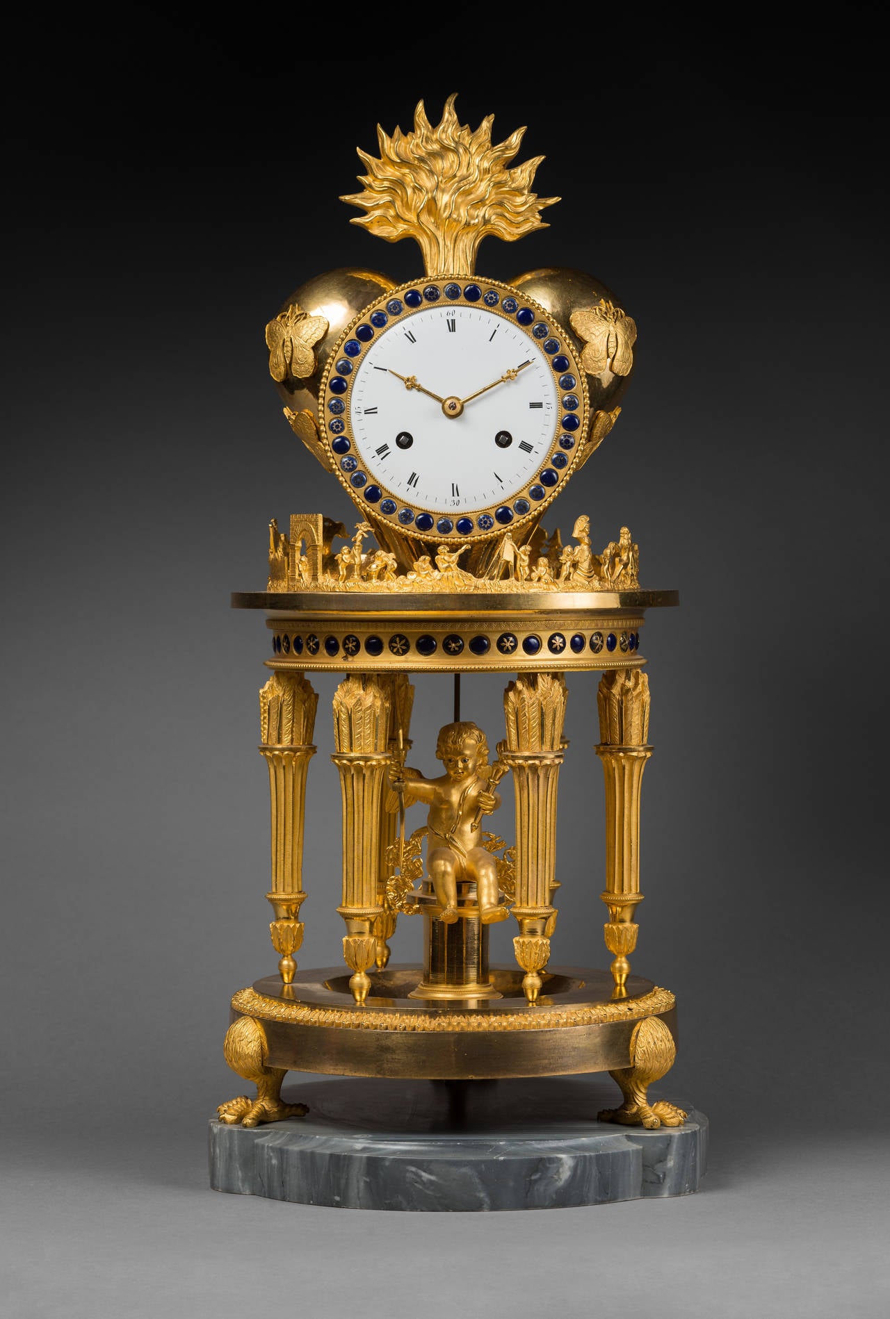 Case Attributed to Jean-Simon Deverberie (1764–1824).

Rare chased and gilt bronze mantel clock 
“The Temple of Love” 

Paris, Directoire period, circa 1795. 
Dimensions: Height 51 cm; diameter 23 cm.

The enamel dial indicates the hours in