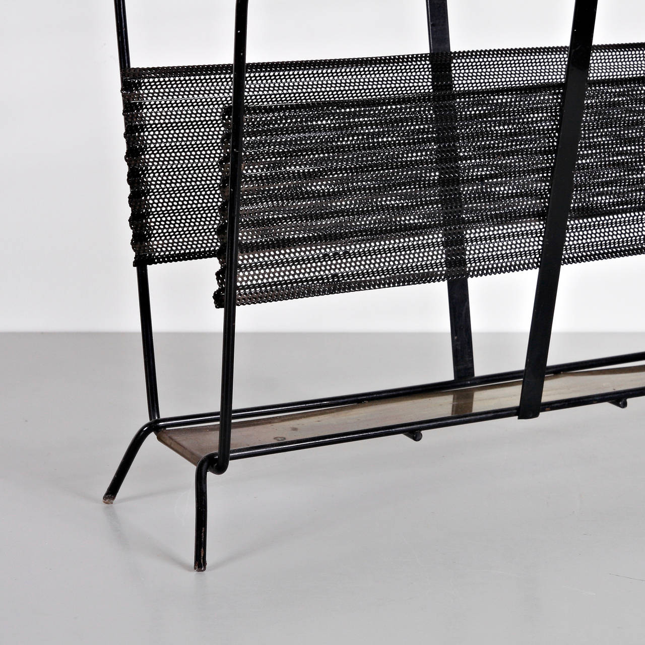 Magazine holder designed by Mathieu Matégot.
Model Harpers.
Manufactured by Ateliers Matégot (France) circa 1950.
Folded, perforated metal lacquered in black and brass detail.

In good original condition, with minor wear consistent with age and