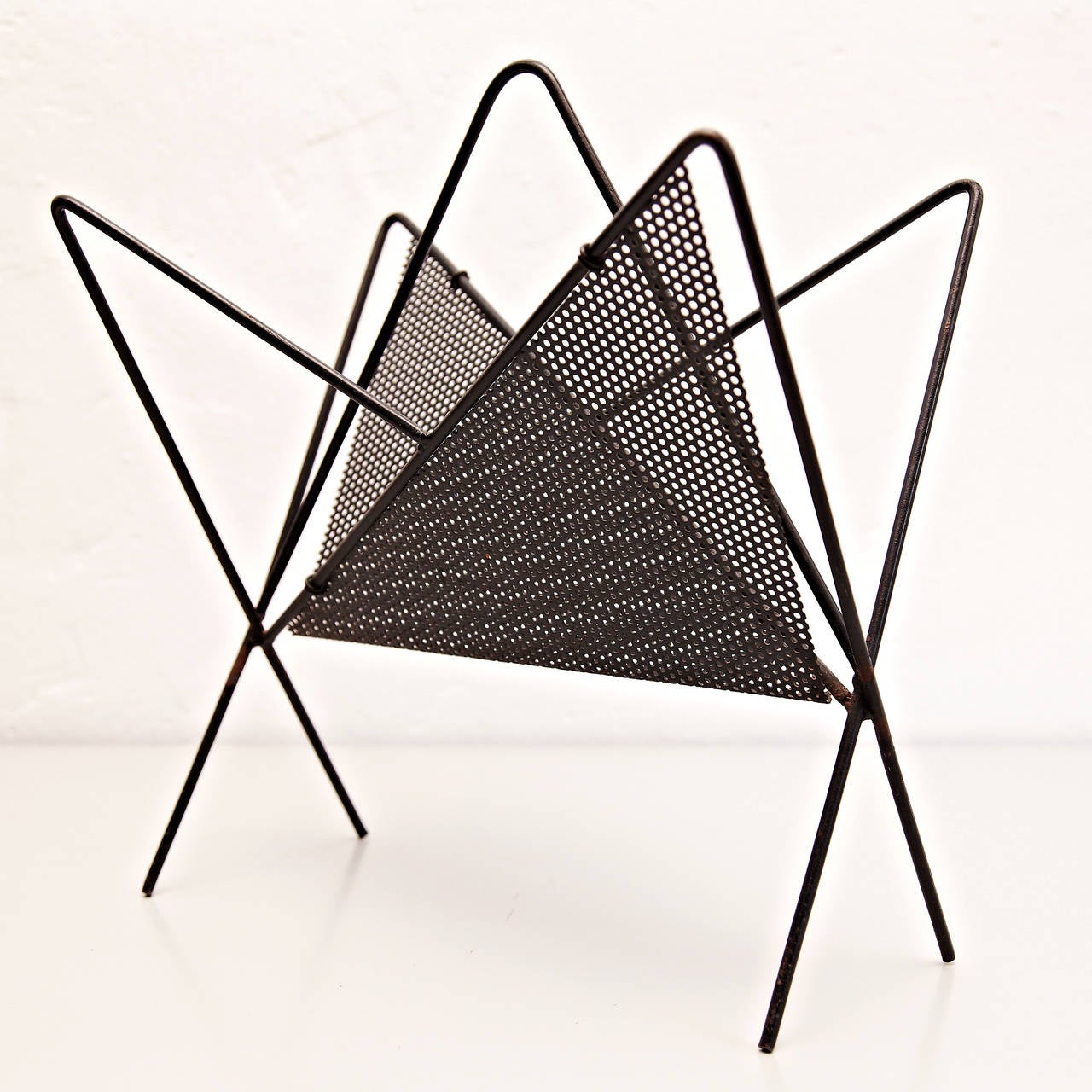 Magazine holder, model Harpers, designed by Mathieu Matégot.
Manufactured by ateliers Matégot (France), circa 1950.
Folded, perforated metal.

In good original condition, with minor wear consistent with age and use, preserving a beautiful