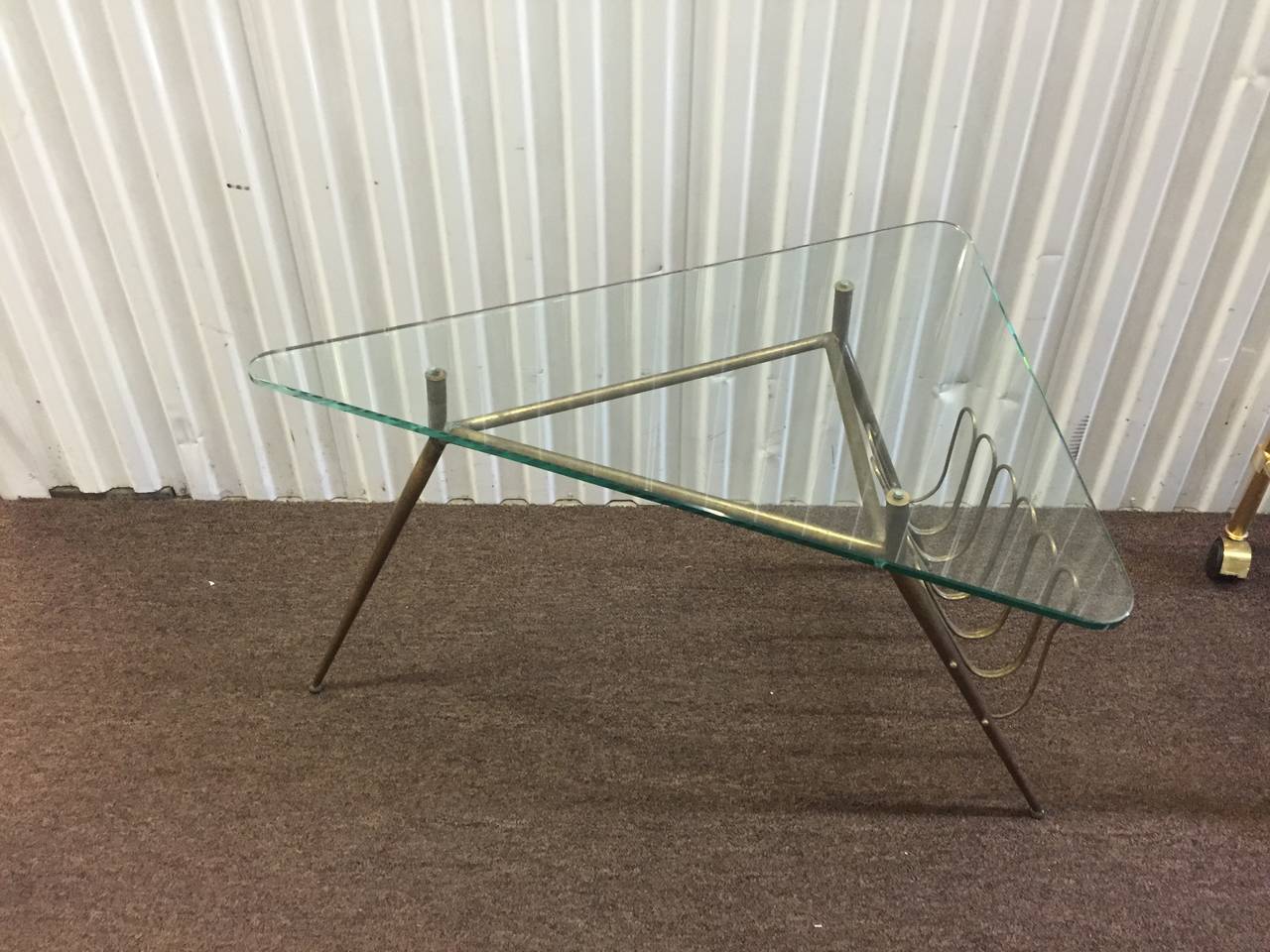 A vintage 1960s Gio Ponti style brass coffee or cocktail table with magazine rack and 1/2 inch thick triangular glass top. Good vintage condition with age appropriate wear and patina.