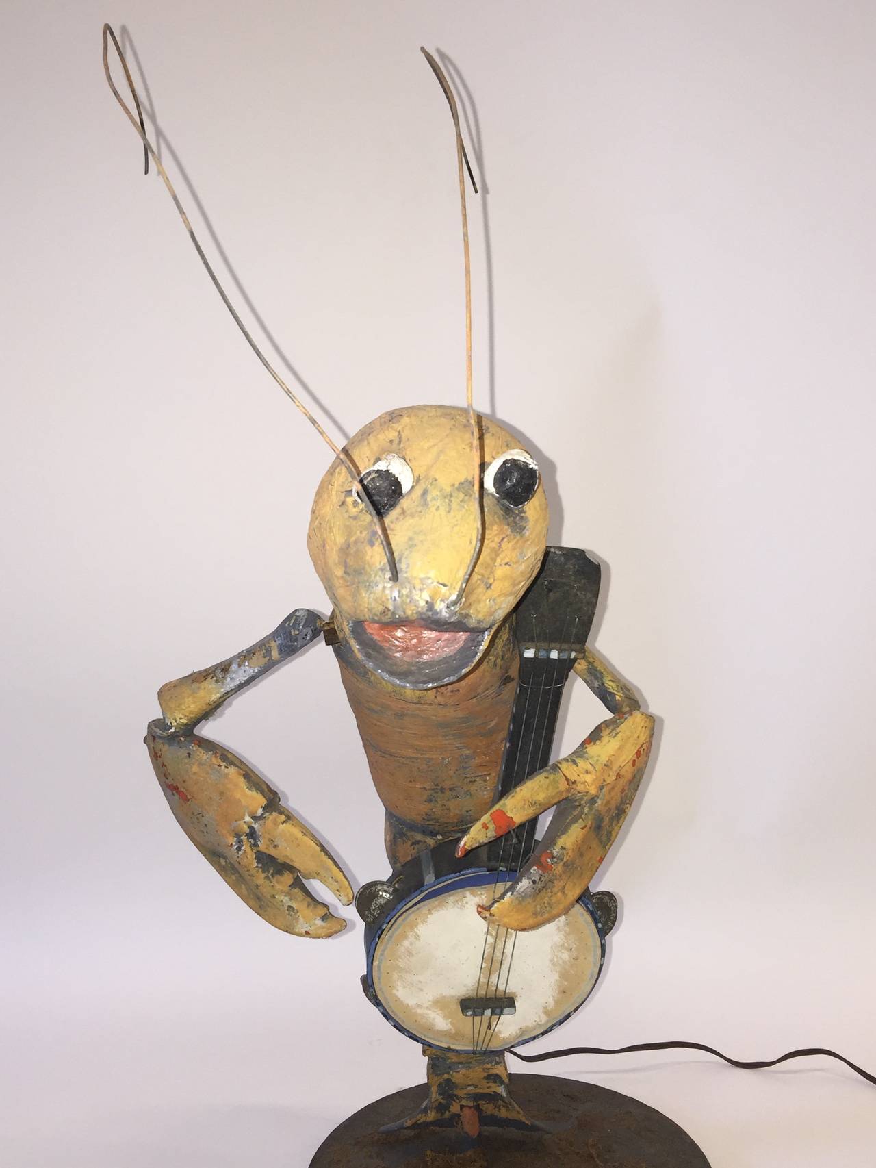 This charismatic lobster is handmade using papier mâché, with a small toy banjo that when plugged in he plays with his claw whilst his head rotates as to simulate his singing. Mounted on a painted round wood base decorated with moss he is a great