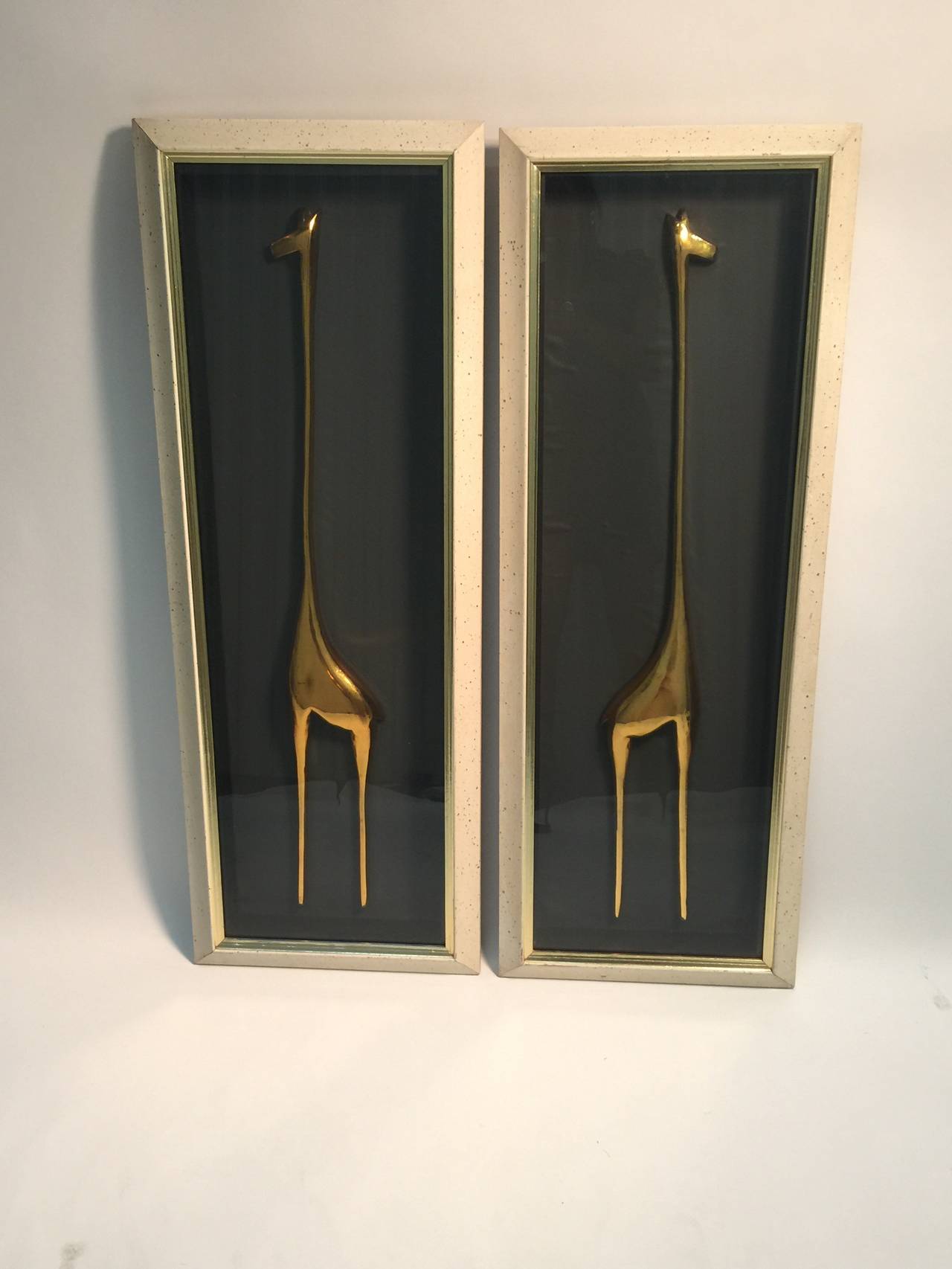 A mint pair of mid century gold glazed ceramic abstract giraffes encased in custom cream and gold spattered painted glass shadowbox style frames.Set against a matte black background they are a striking pair of wall Art.
Reminiscent of the stylized