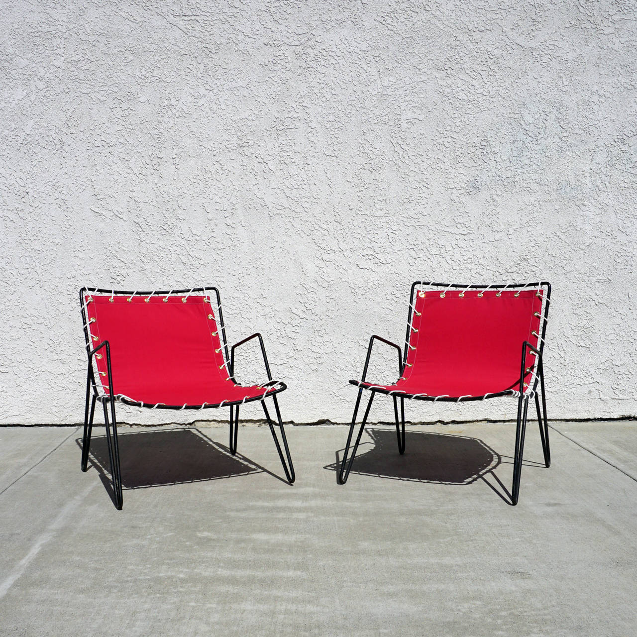 A pair of 1950s vintage iron and canvas sling chairs. The new slings are made of Sunbrella fabric.
