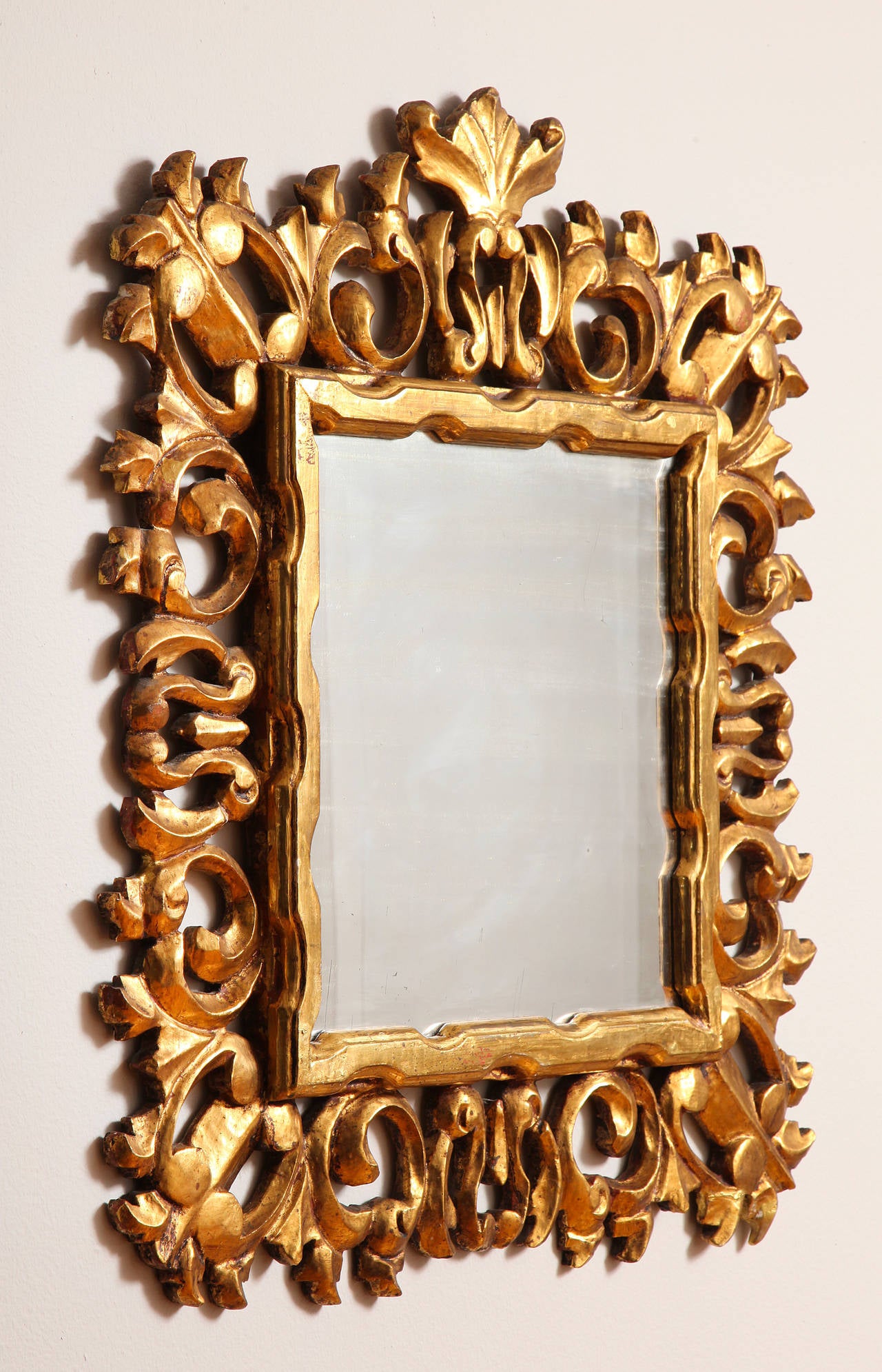 An exuberantly carved and gilded Italian Baroque style mirror frame with its original mirror glass.
