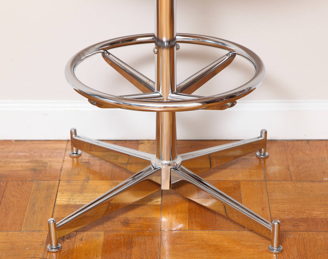 A set of three chrome bar stools with caramel colored vinyl seats and cushion back straps and rings and arm supports; the chrome columnar base with foot support. 
By Daystrom Furniture of Boston.