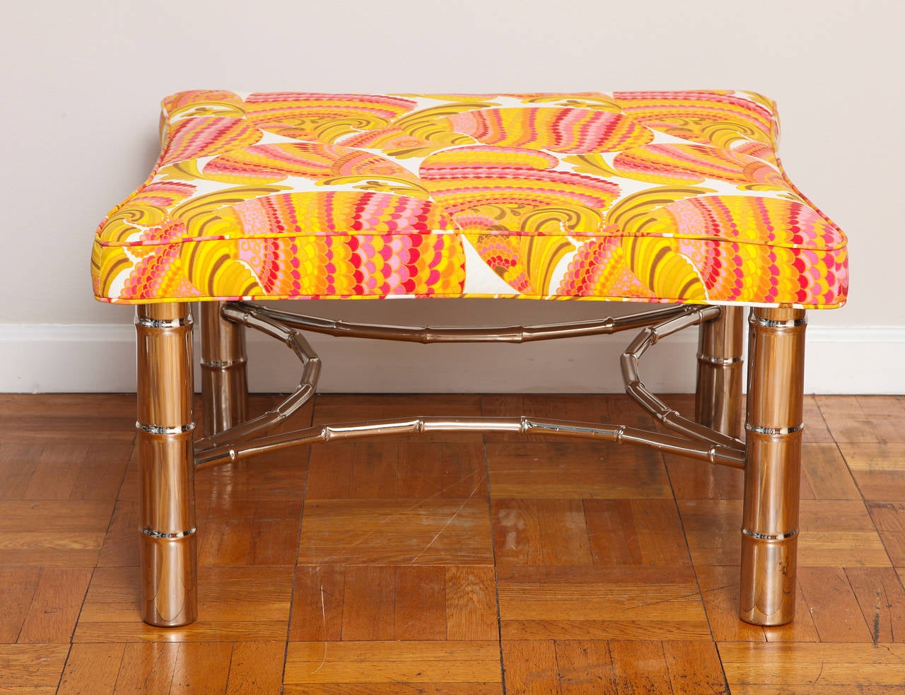 A faux bamboo ottoman with chrome legs and stretcher, the top covered in Emilio Pucci fabric.