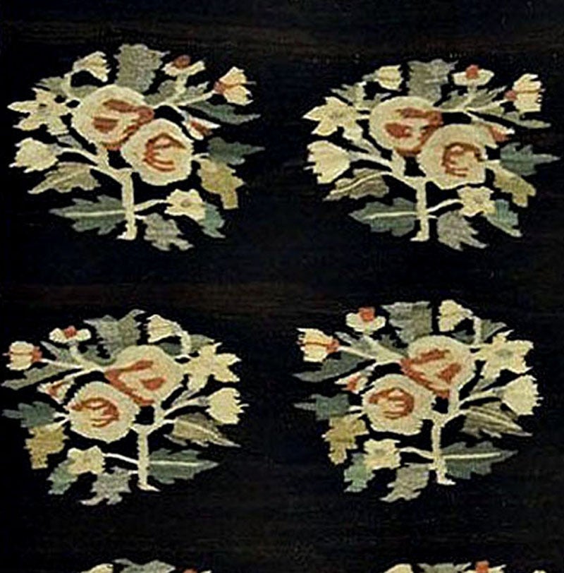 An antique circa 1900 Bessarabian Kilim from Romania, the black ground broken up by five groups of three floral heads.