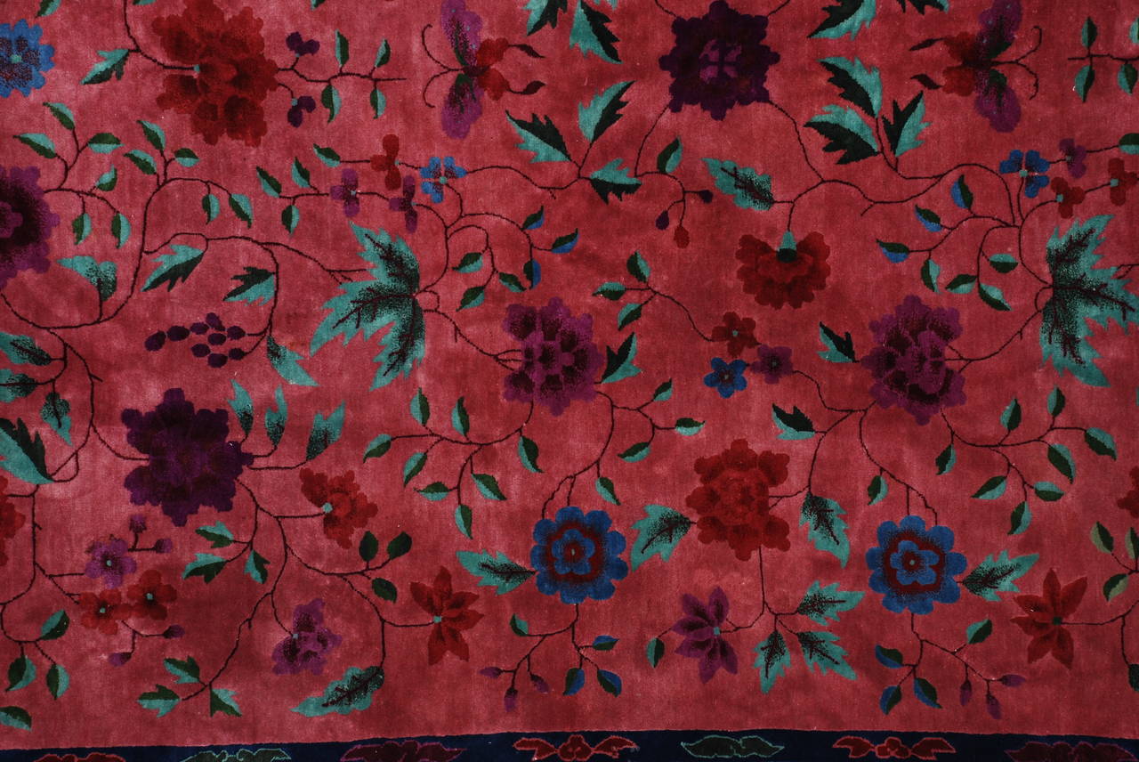 This circa 1930 Art Deco Chinese Oriental rug measures 9’0” X 11’7”. It is a very beautifully drawn Deco Chinese with a large vine and flower design with bunches of grapes hanging down in deep purple, lavender, green, blue, red, and rust.  There are