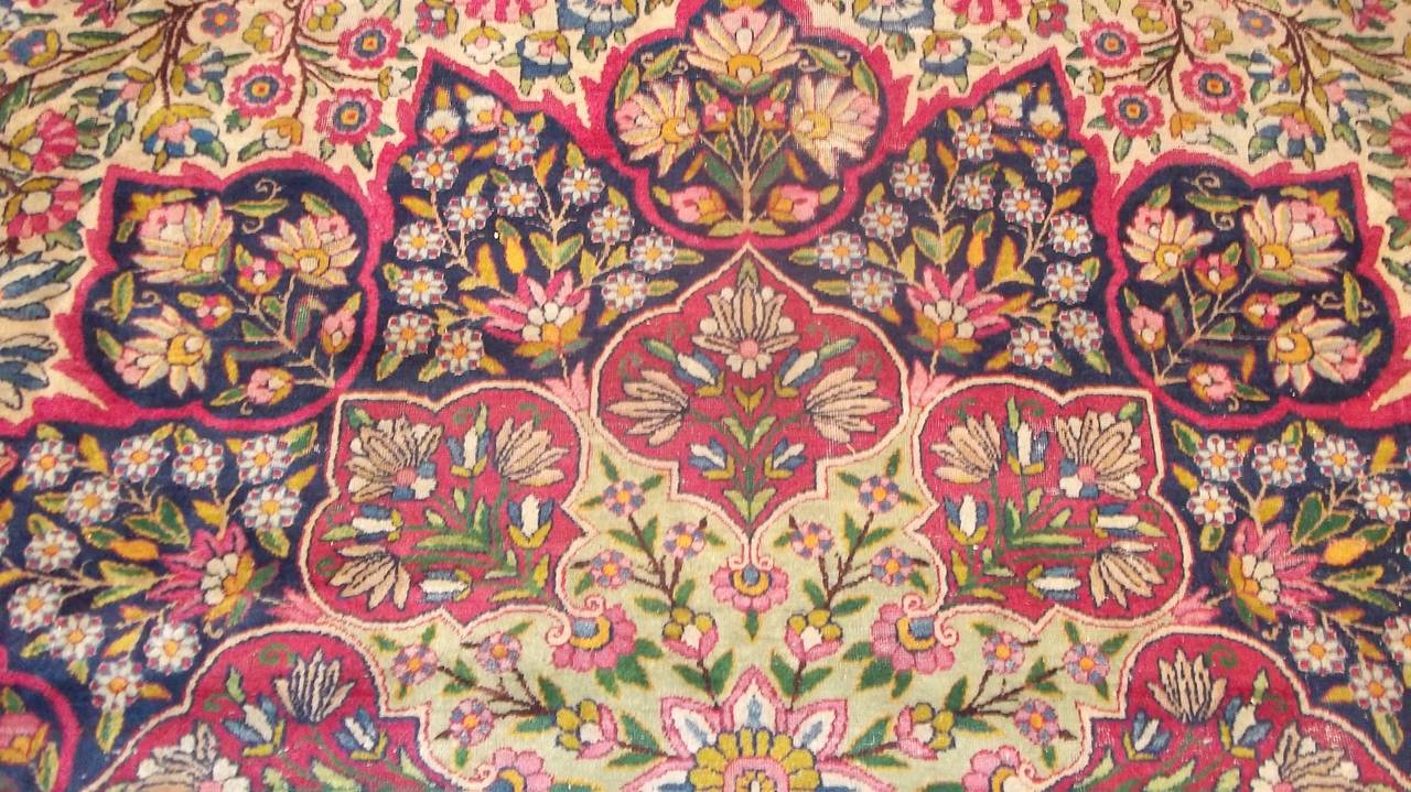 This circa 1890 Laver Kerman (INV 7385) Antique Oriental Rug measures 12’3” X 16’0” (374 x 486 cm). It has an ivory field completely covered in green foliage with touches of red and magenta. There is a huge Sunburst floral medallion. The borders are