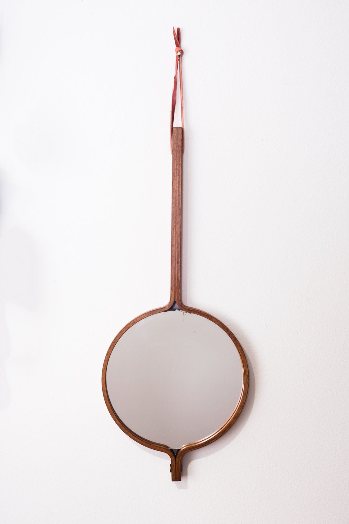 Teak mirror by Hans-Agne Jakobsson for Hans-Agne Jakobsson Markaryd, Sweden, 1950s. Can be used both as a hand mirror or as a wall mirror hung by its leather strap. Smooth lines and natural wood grain.

After studying architecture Hans-Agne