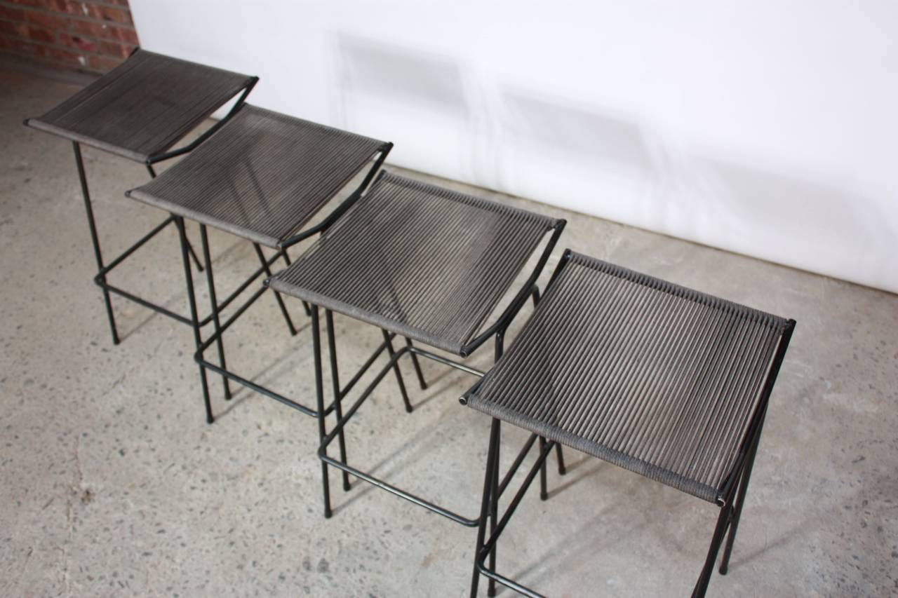 This set of four 1950s Allan Gould iron stools retains their original rope seats. The stools are all in excellent, vintage condition with only age-appropriate, minor wear to the frames and some light fading to the surface of the rope seats.