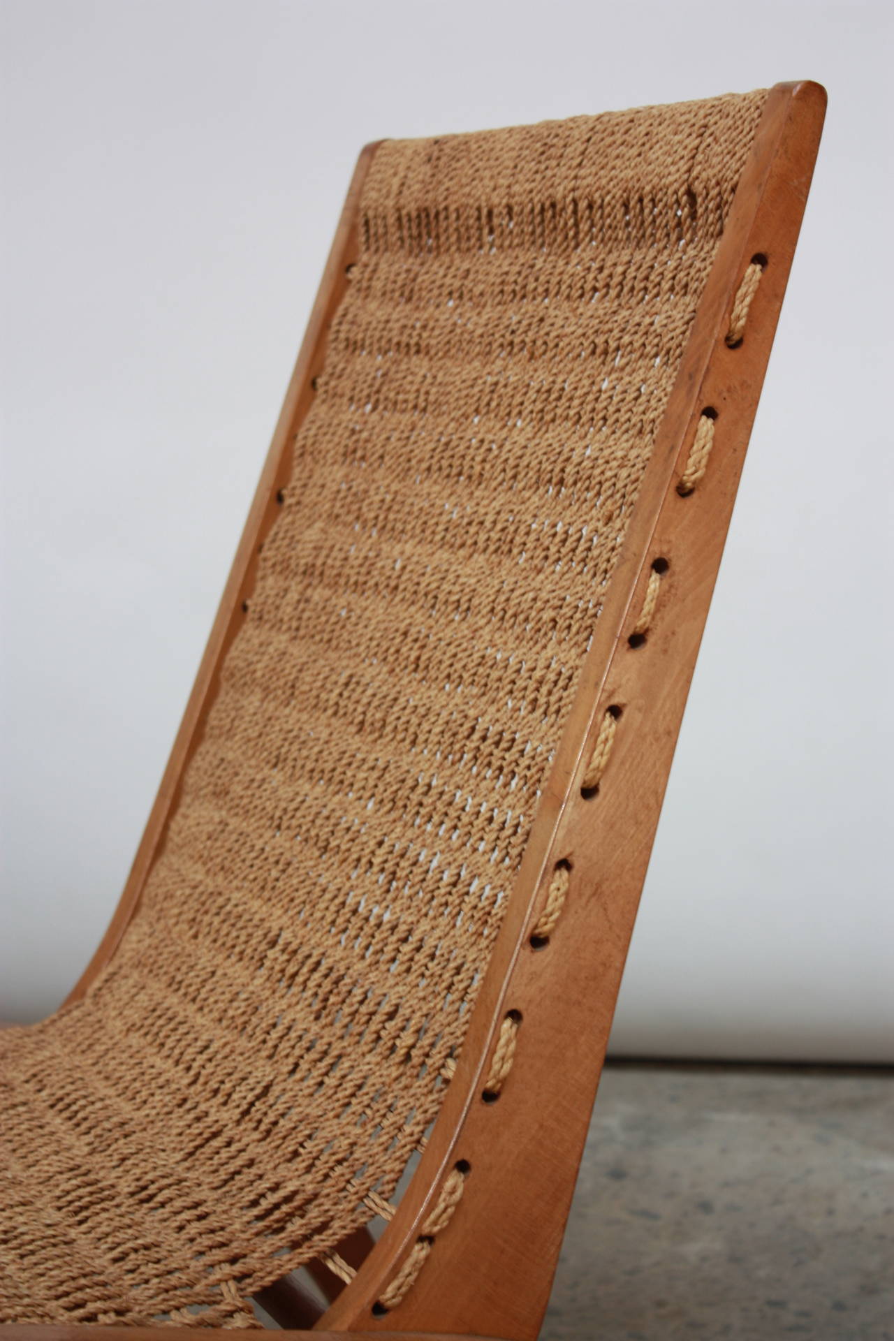 This unique Scandinavian accent chair features a woven rope seat with a carved wood frame. The design is reminiscent of Edward Durell Stone's seating design for Fulbright, but the piece is unsigned and unattributed.