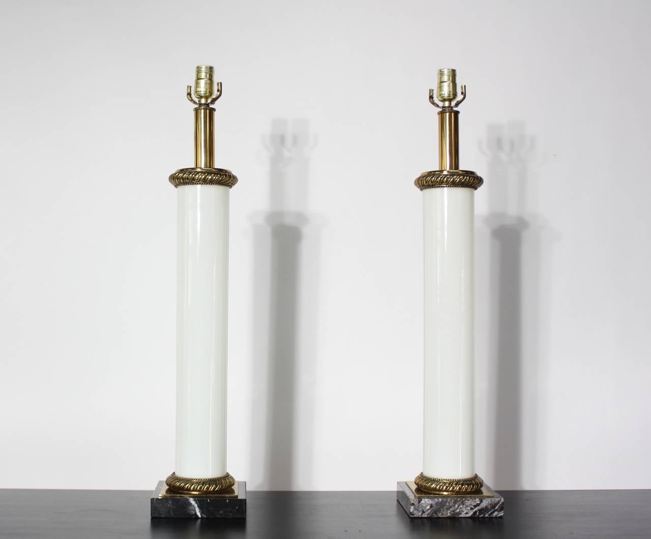 This pair of tables lamps was designed in the 1950s by Paul Hanson of New York. They are comprised of opaline glass, marble, and brass and come with the original shades. The lamps themselves are in excellent, vintage condition. The shades, one in