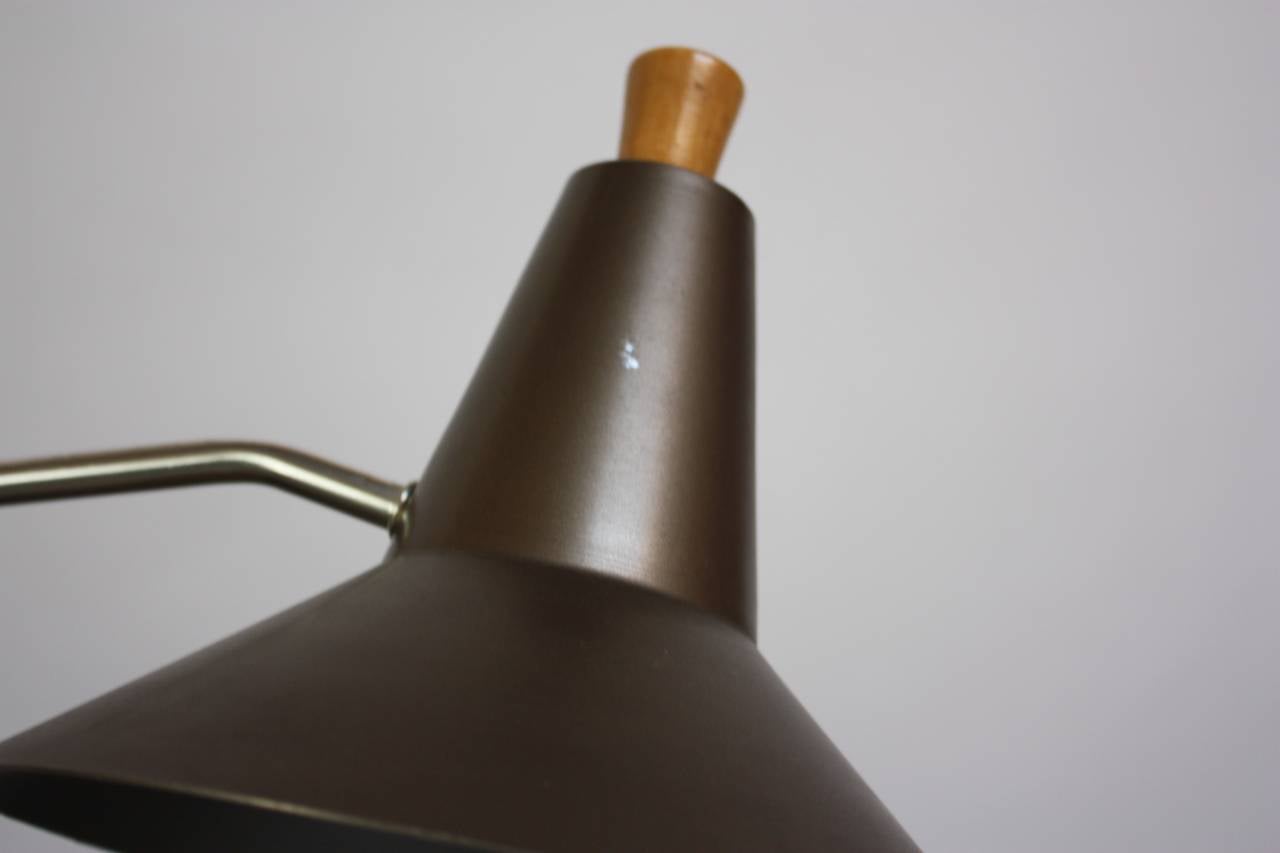 This versatile table lamp is comprised of an aluminum shade / base, brass adjustment, and wooden arm (likely pine). Both shade and arm are adjustable.
The diameter of the base is: 5.5