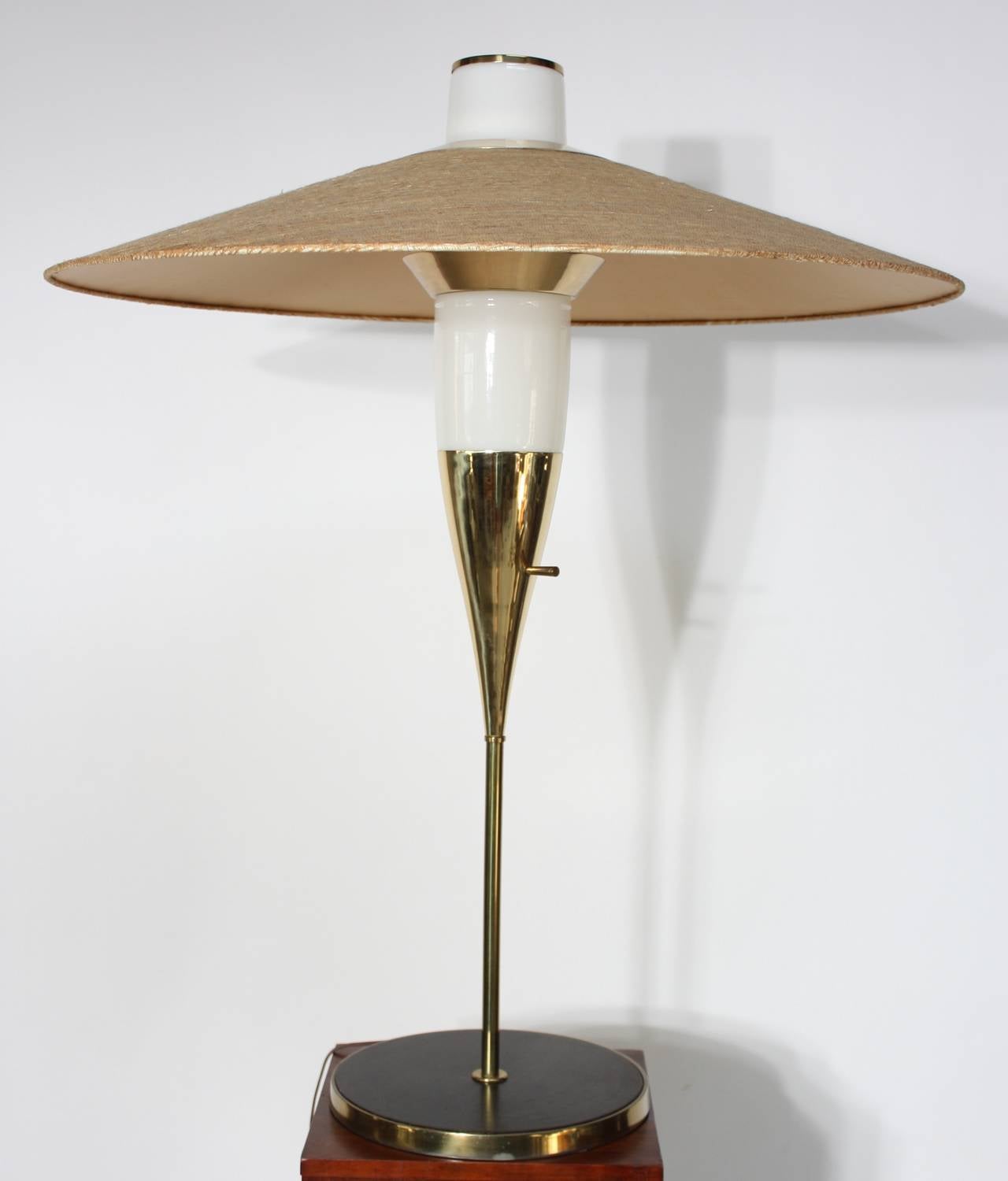 This spectacular table lamp is comprised of a rosewood veneer / brass-lined base, solid brass stem, cased glass shade, and oversized grass-cloth shade. This lamp has design elements of both Laurel and Gerald Thurston, but it is unsigned /