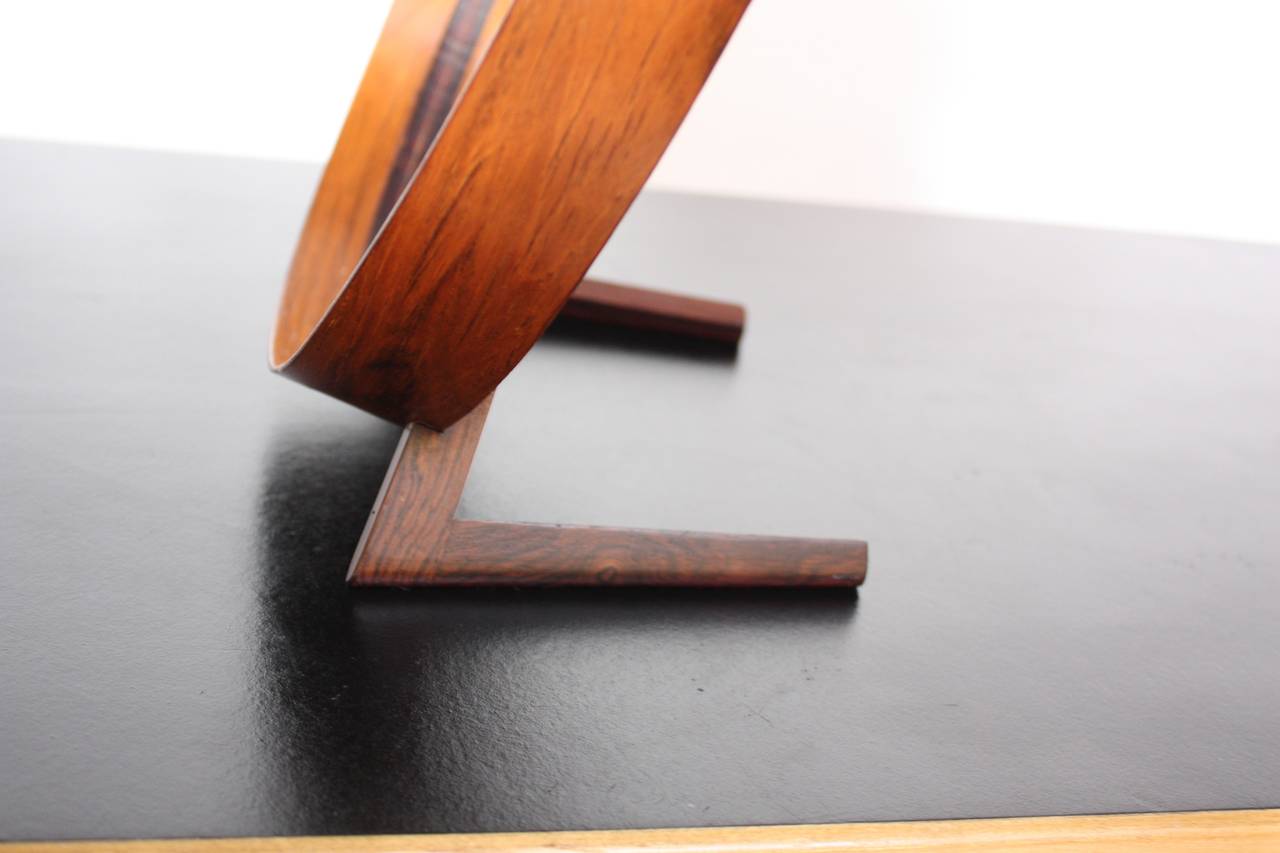 This rare rosewood and leather table mirror was designed by Uno and Östen Kristiansson for Luxus. The elegant simplicity of the form is nicely contrasted with the texture and richness of the rosewood. 
There is a small spot where the leather has