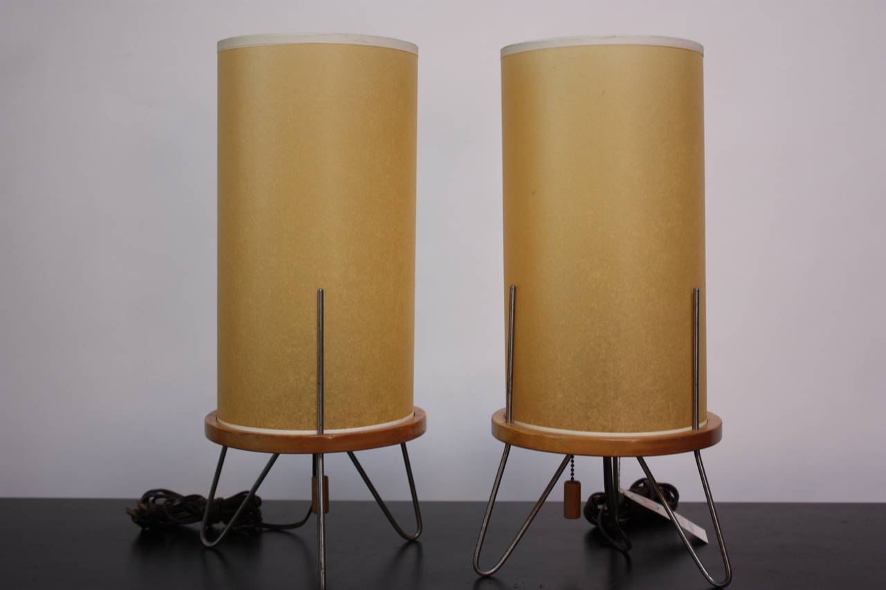 This pair of 1950s Heifetz lamps still retains the original tag and appears to never have been used. The nickel-plated tripod steel bases hold the cylindrical shades in place. The platforms of each lamp and the pull string finials are birch.
This