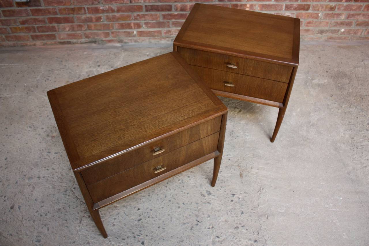 This scarcely seen pair of mahogany nightstands was designed by Ray Sabota for John Stuart. The sculptural legs flare out and, in conjunction with the enamel pulls, add nice contrast to the otherwise simplistic, clean-lined design. The chests are