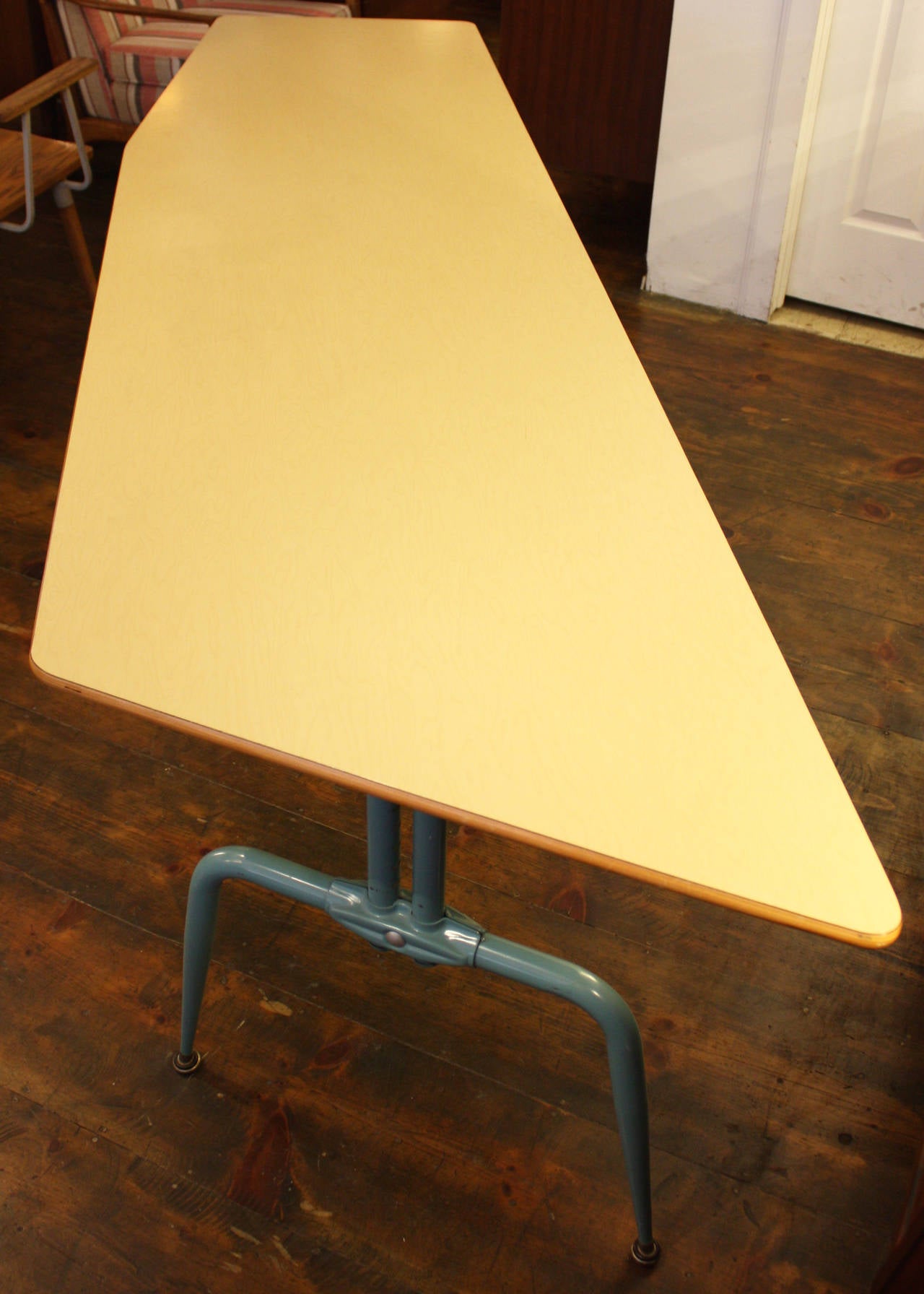 This unique French table is composed of a laminated plywood, asymmetrical top supported by enameled-steel bases which are adjustable. This versatile table can be used as a dining, conference, or writing table. The table bases are flared out in